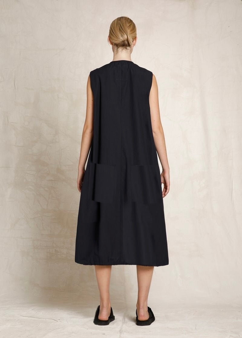 Woman wearing a black sleeveless dress against a neutral background