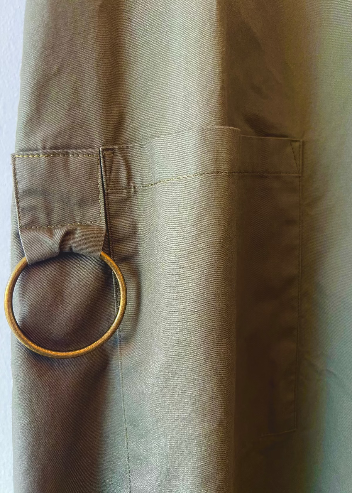 Close-up of a pocket on a beige jacket with a gold ring