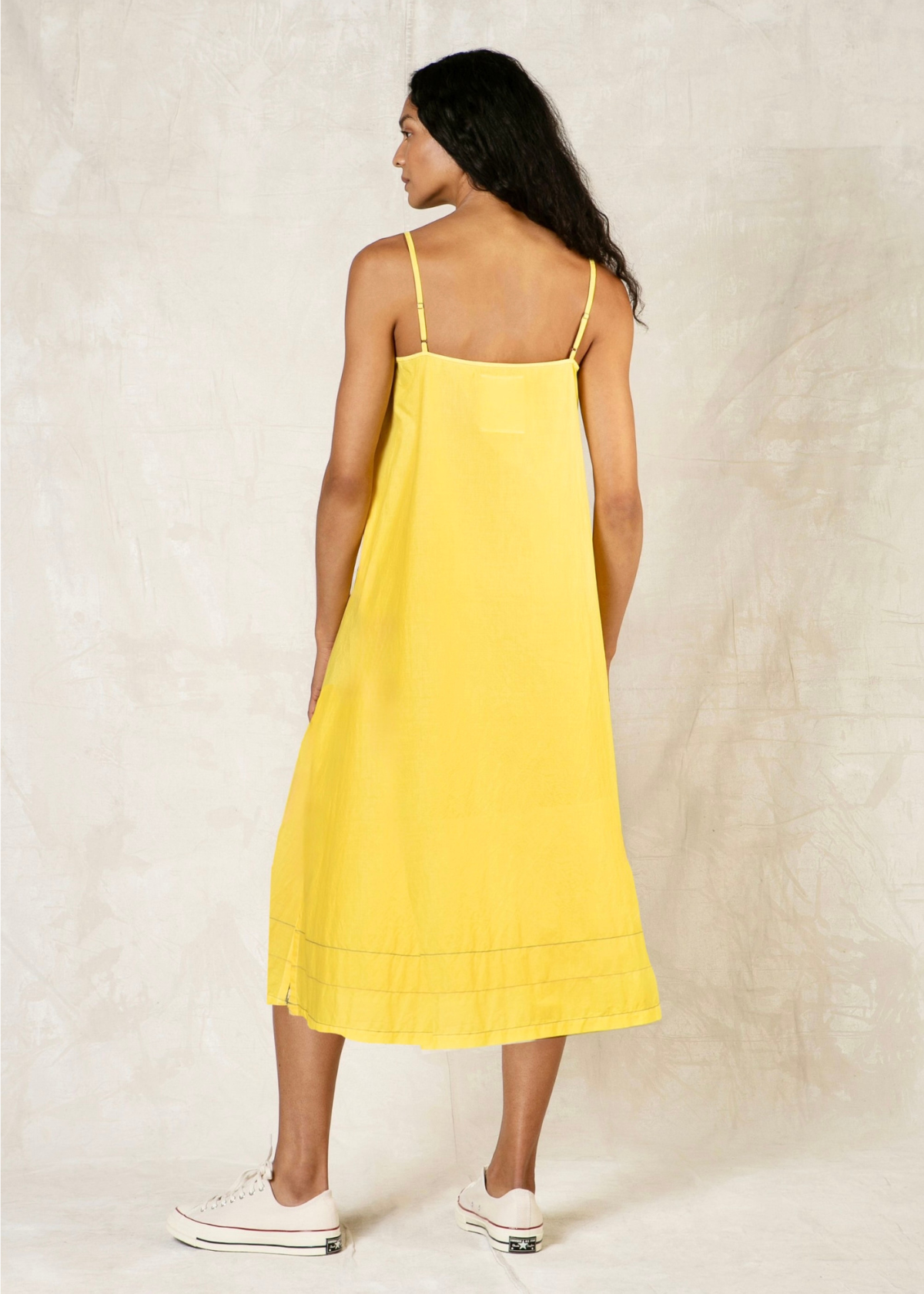 rear view of woman wearing a yellow dress against a plain background
