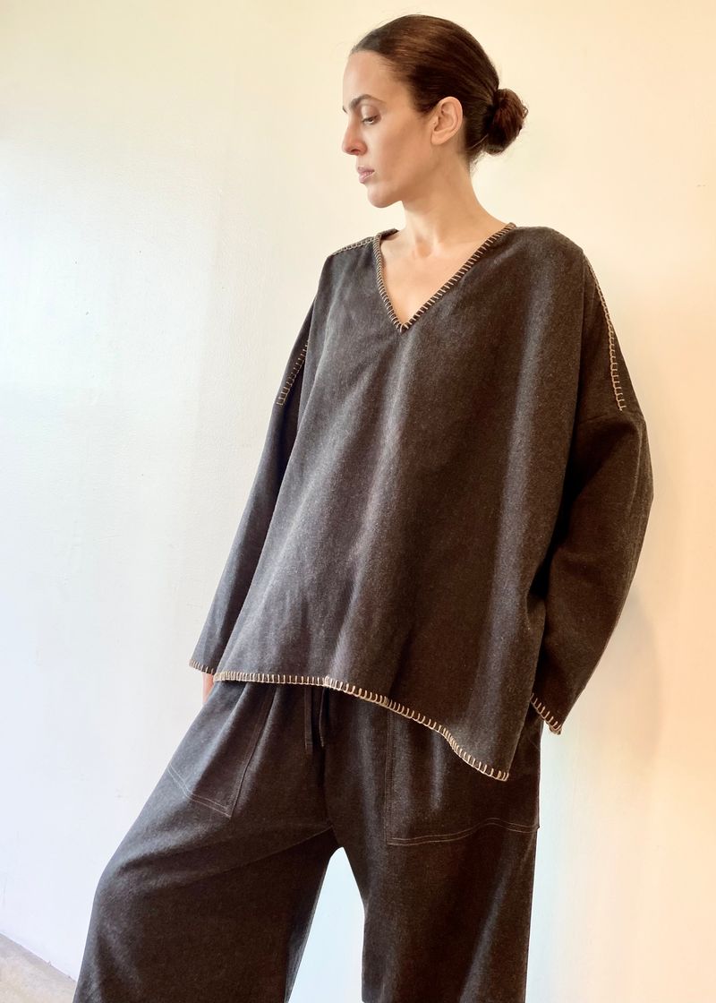 Woman wearing a dark brown oversized flannel sweater and pants against a plain background