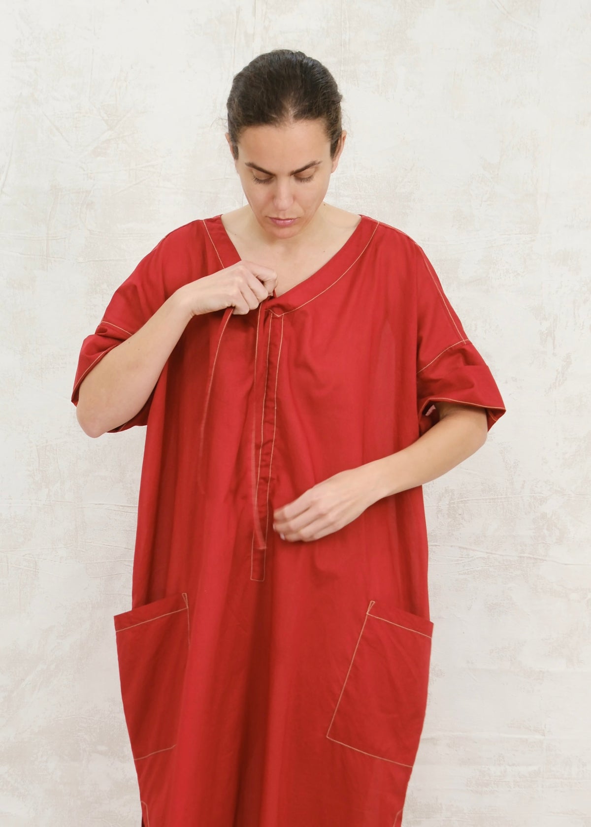 Woman wearing a red dress against a white background and holding pullstring