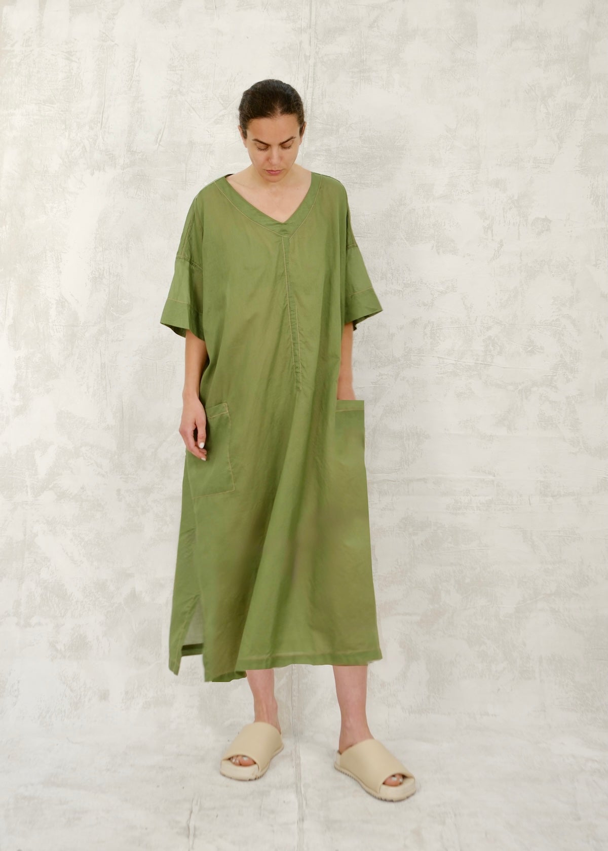 Woman wearing a green dress against a textured white background