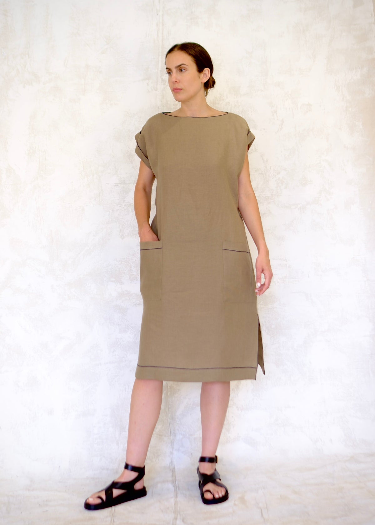 model in khaki colored linen sheath dress with hand in pocket