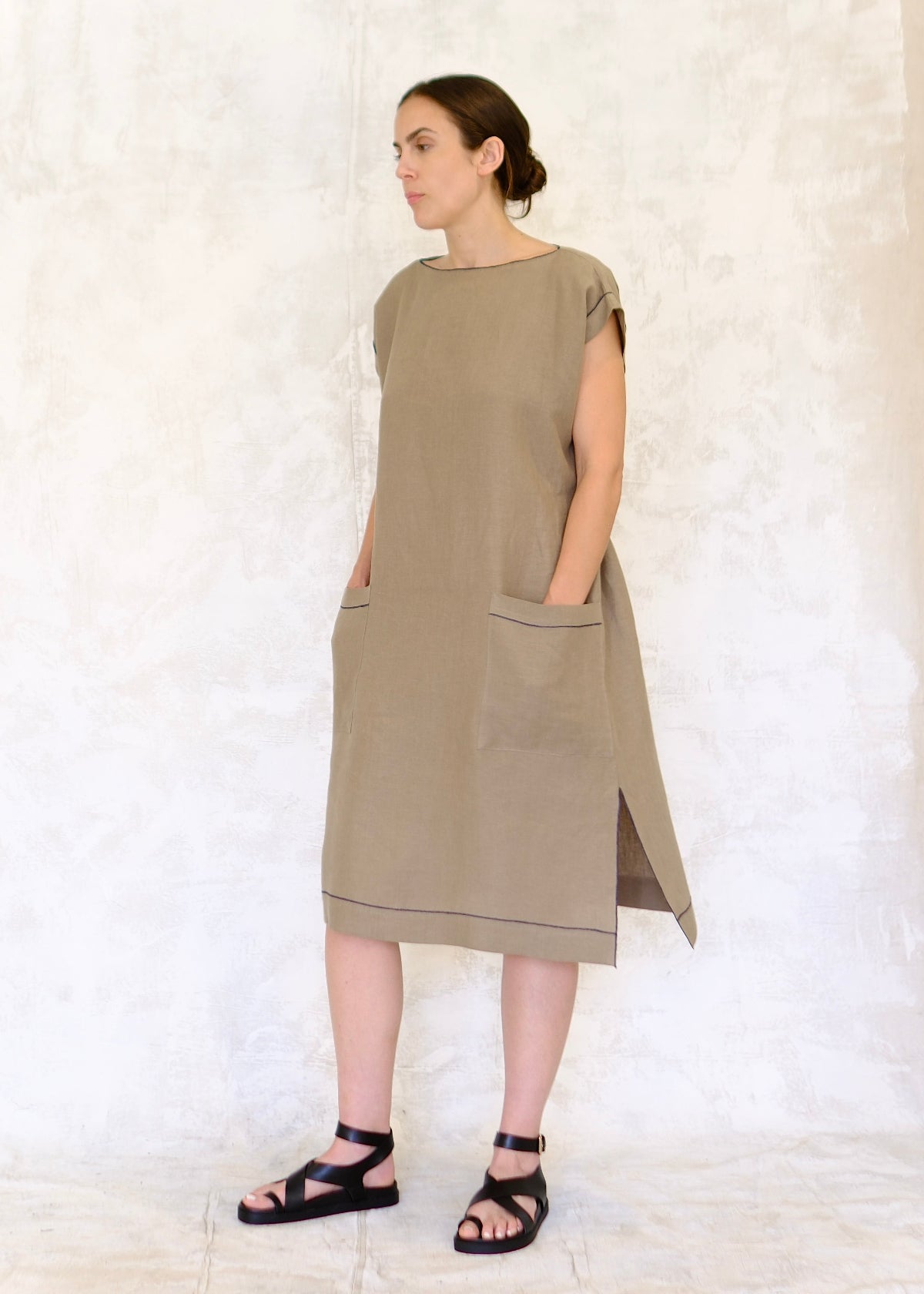 model in khaki colored linen sheath dress with hands in pockets