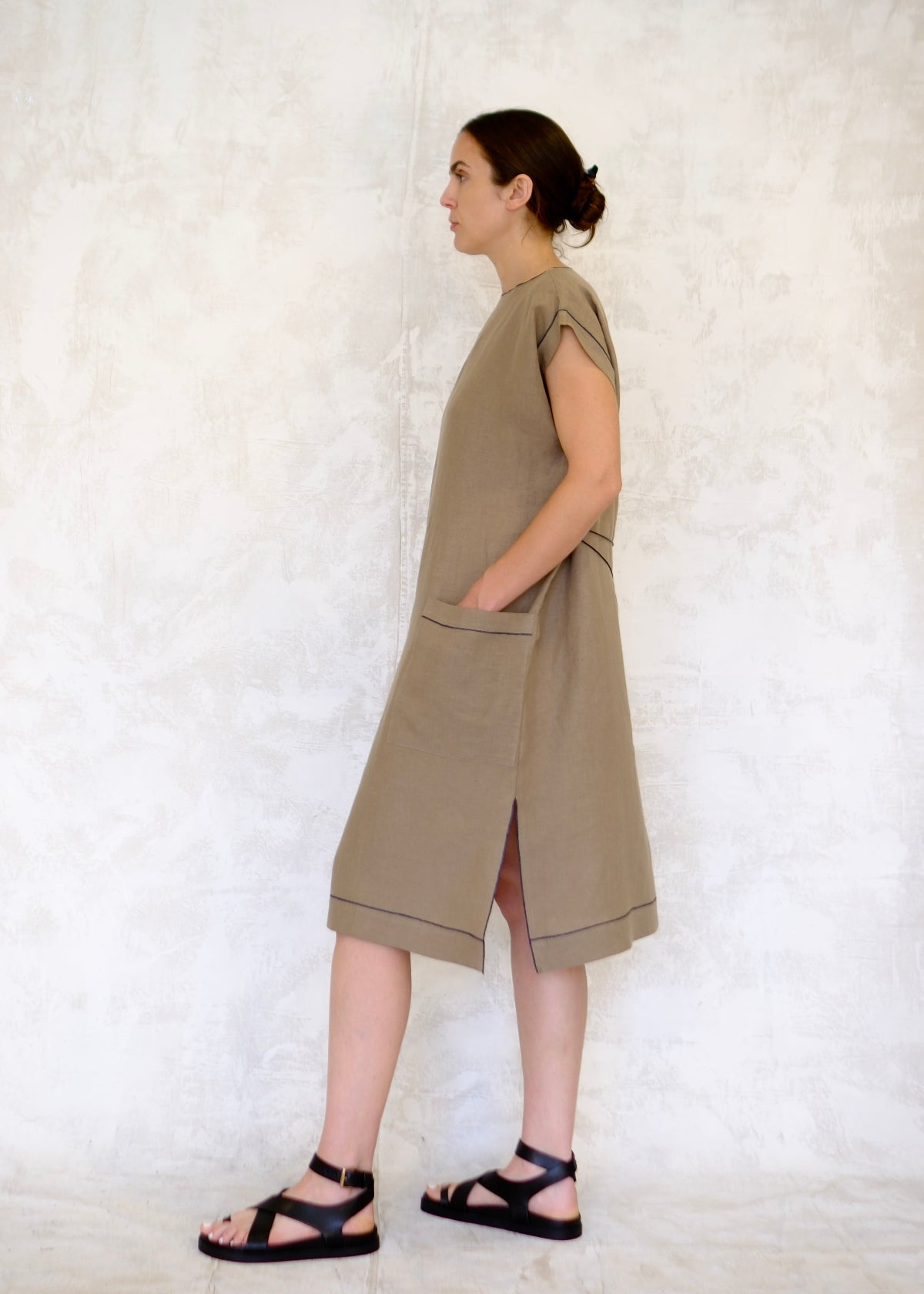 model in khaki colored linen sheath dress with hand in pocket side view