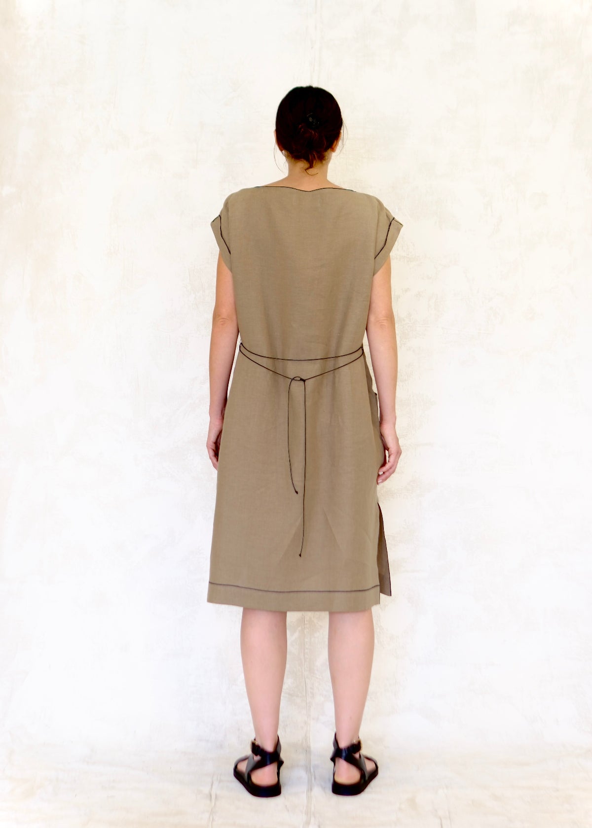 model in khaki colored linen sheath dress loosely belted in back