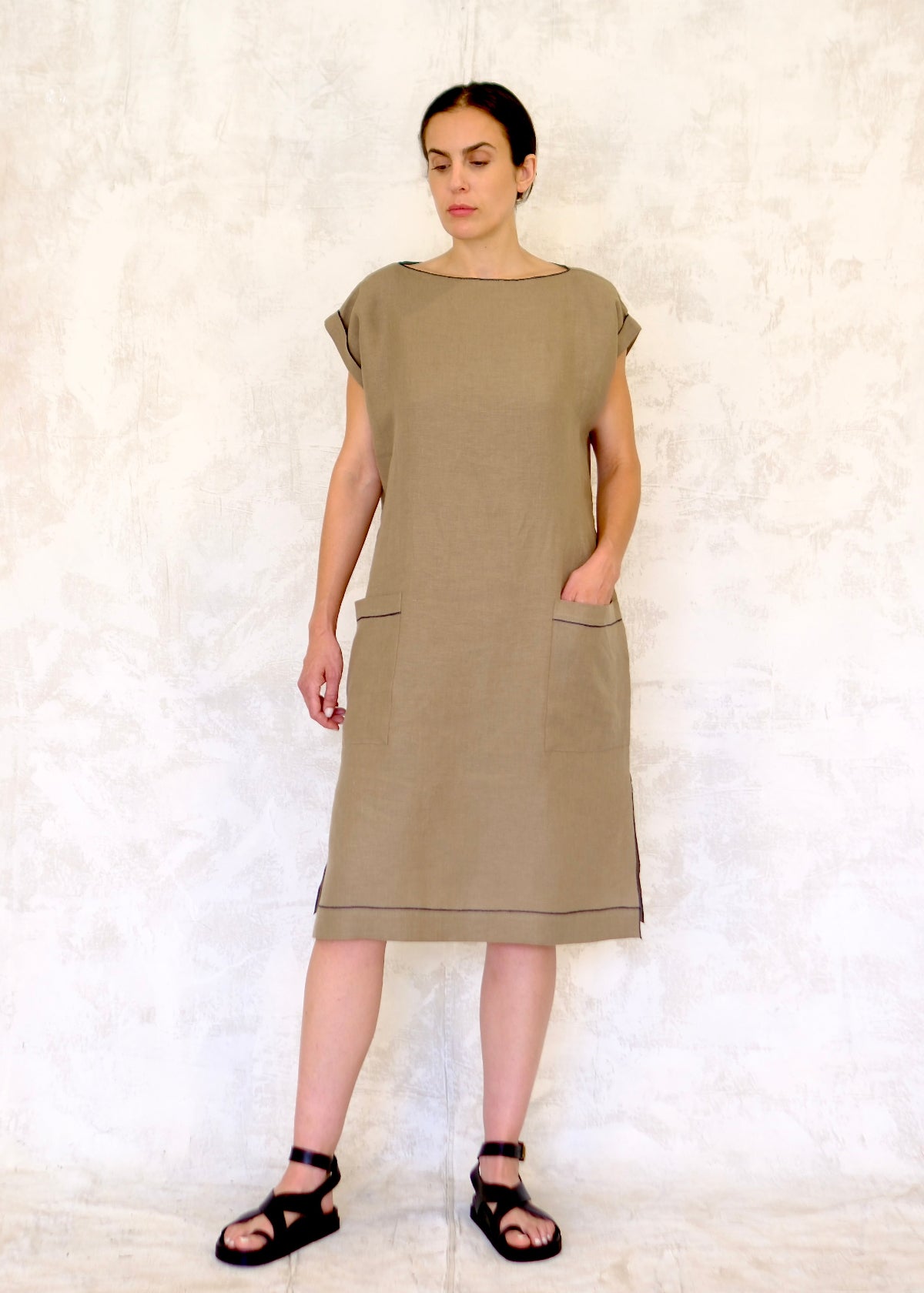 model in khaki colored linen sheath dress with hand in pocket