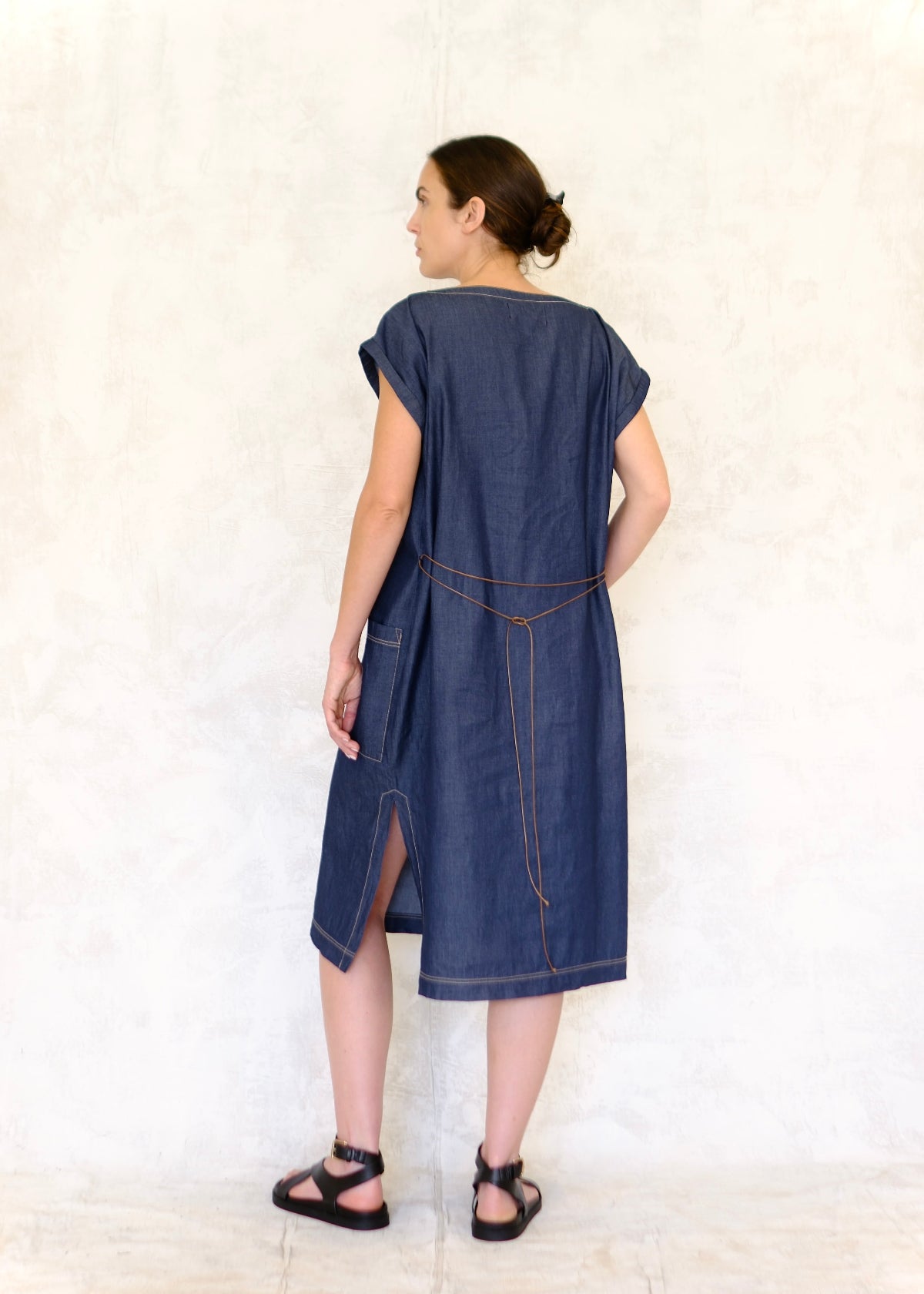 model with loosely belted cap sleeve denim boat neck dress rear view