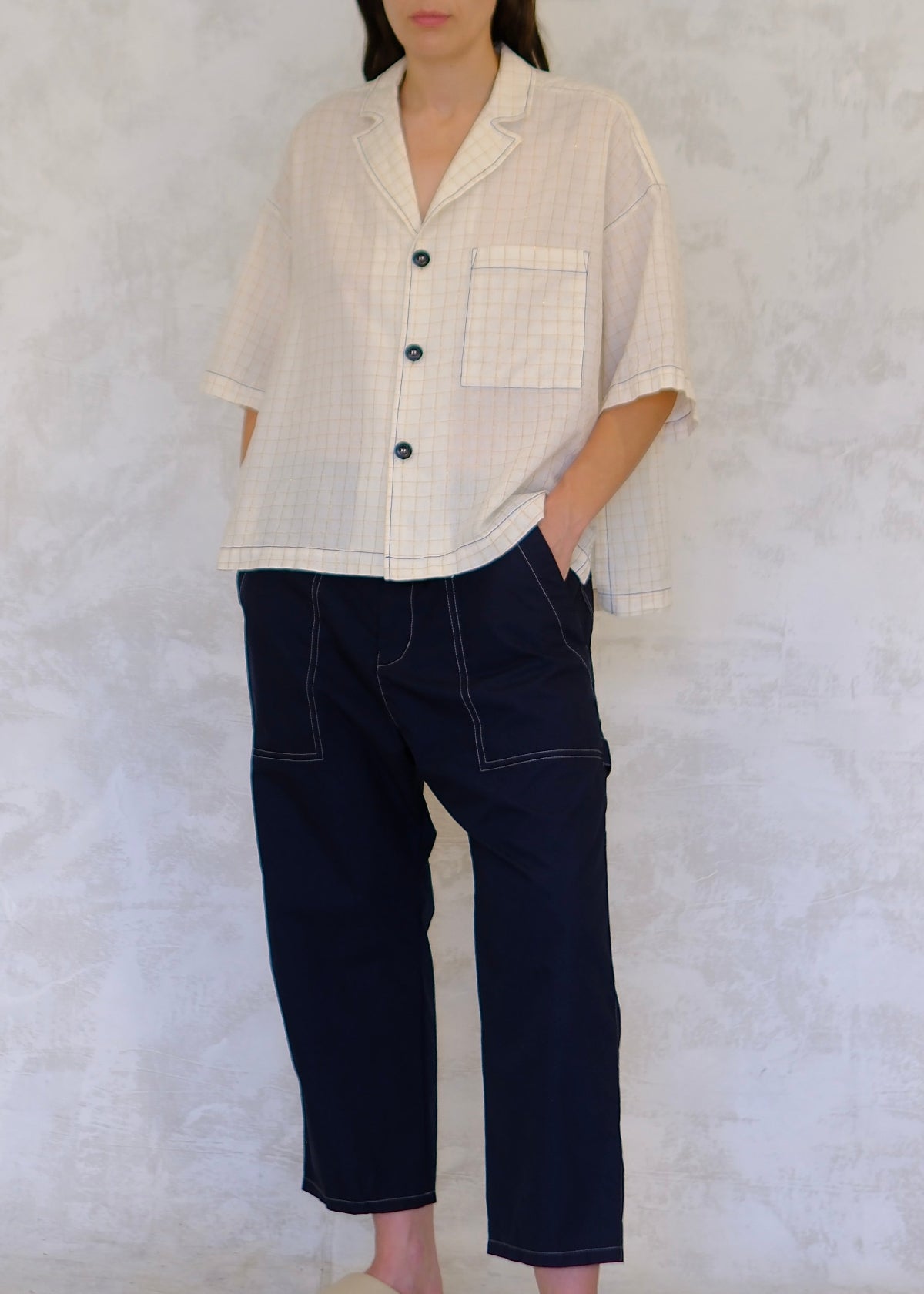Person wearing a light-colored shirt and dark pants against a white background