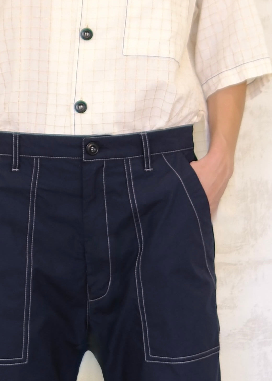 tight shot of navy poplin pants with contrast stitching button waist, pockets