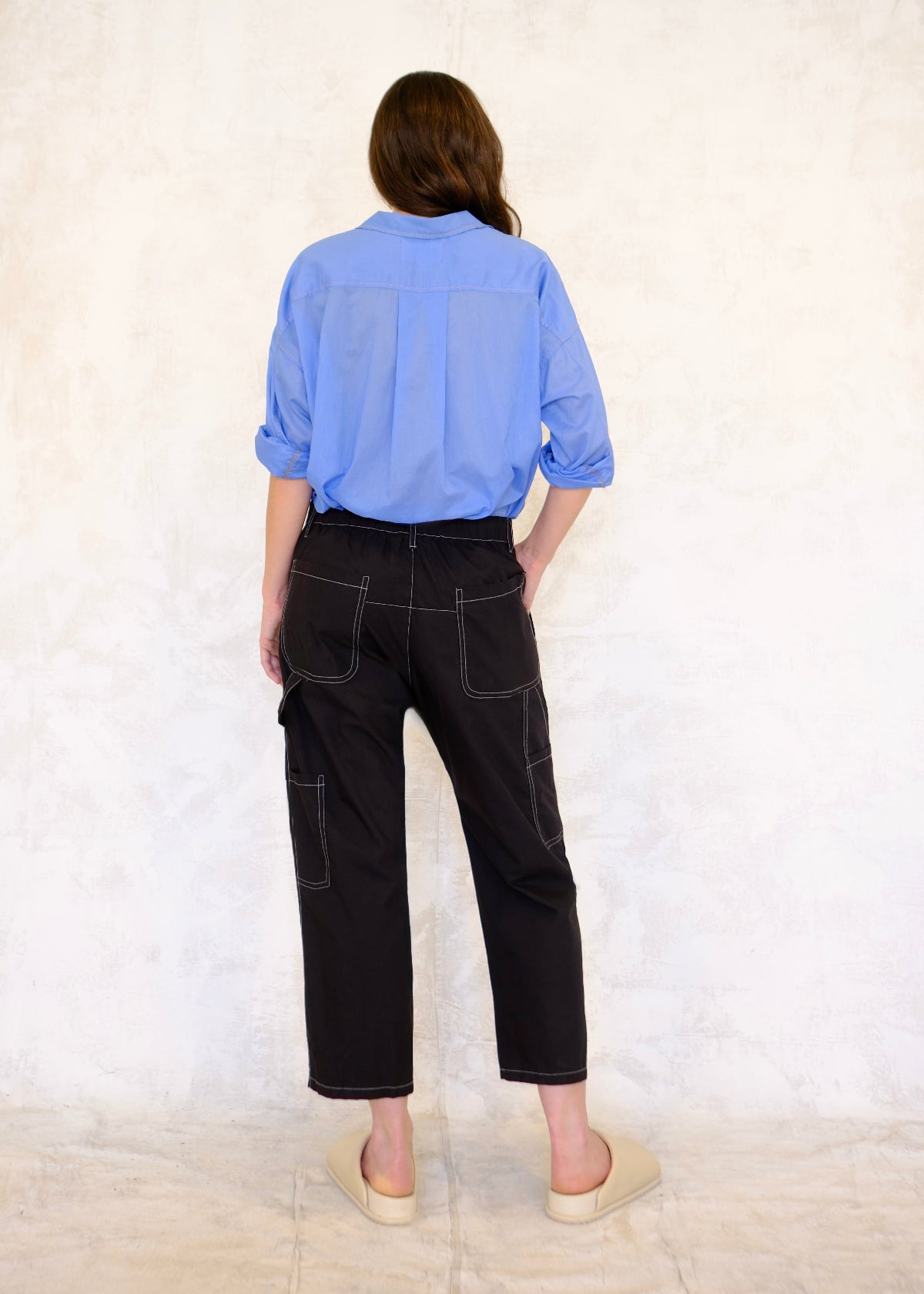 rear view of robins egg blue top with black poplin pants with contrast rear pockets, tool pockets and tool loop