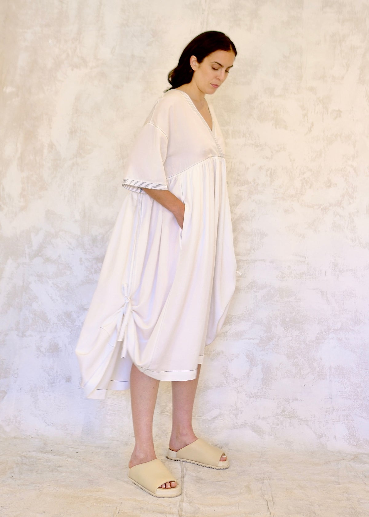 Woman wearing a white dress against a textured white background