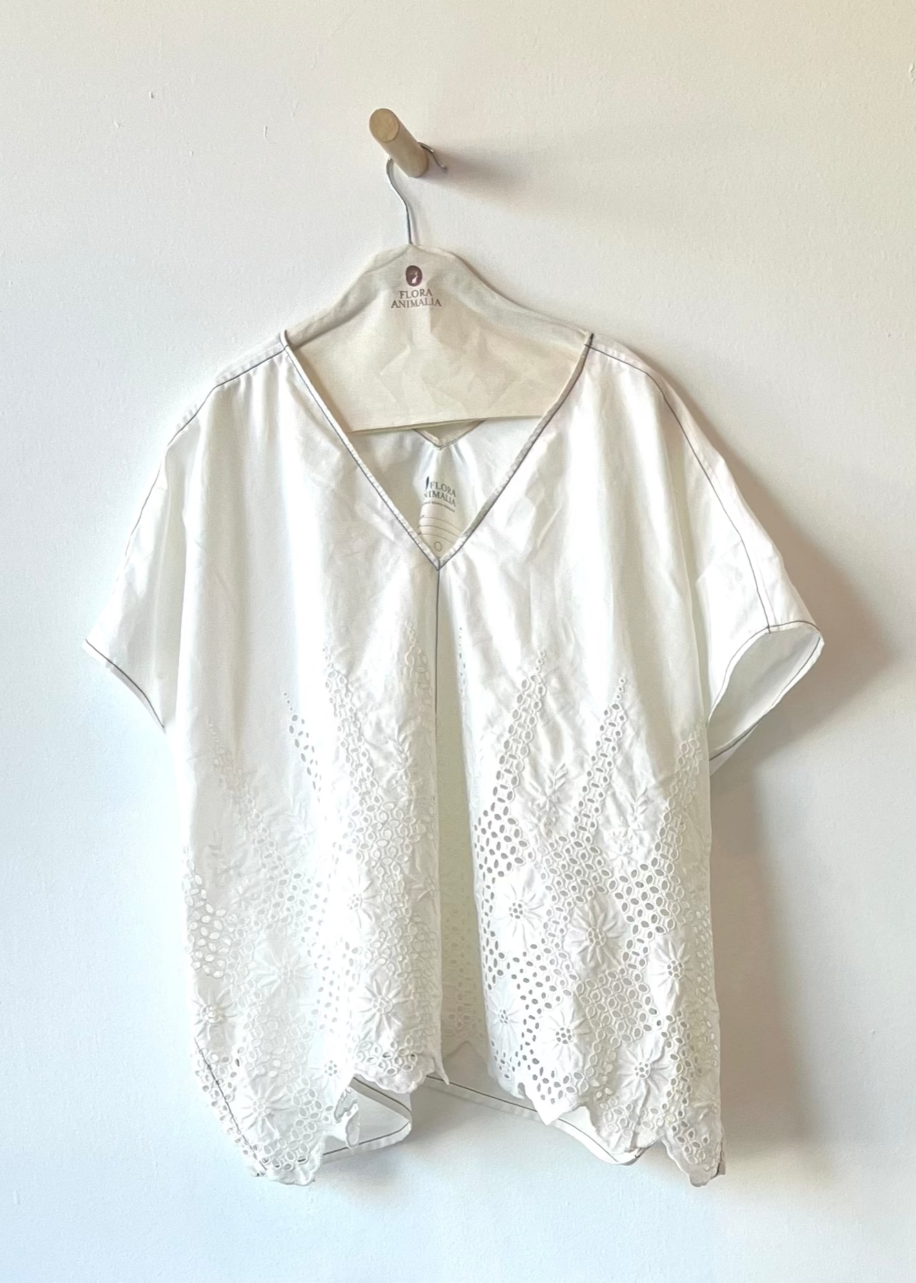 white shirt with eyelet and white embroidery against a white wall