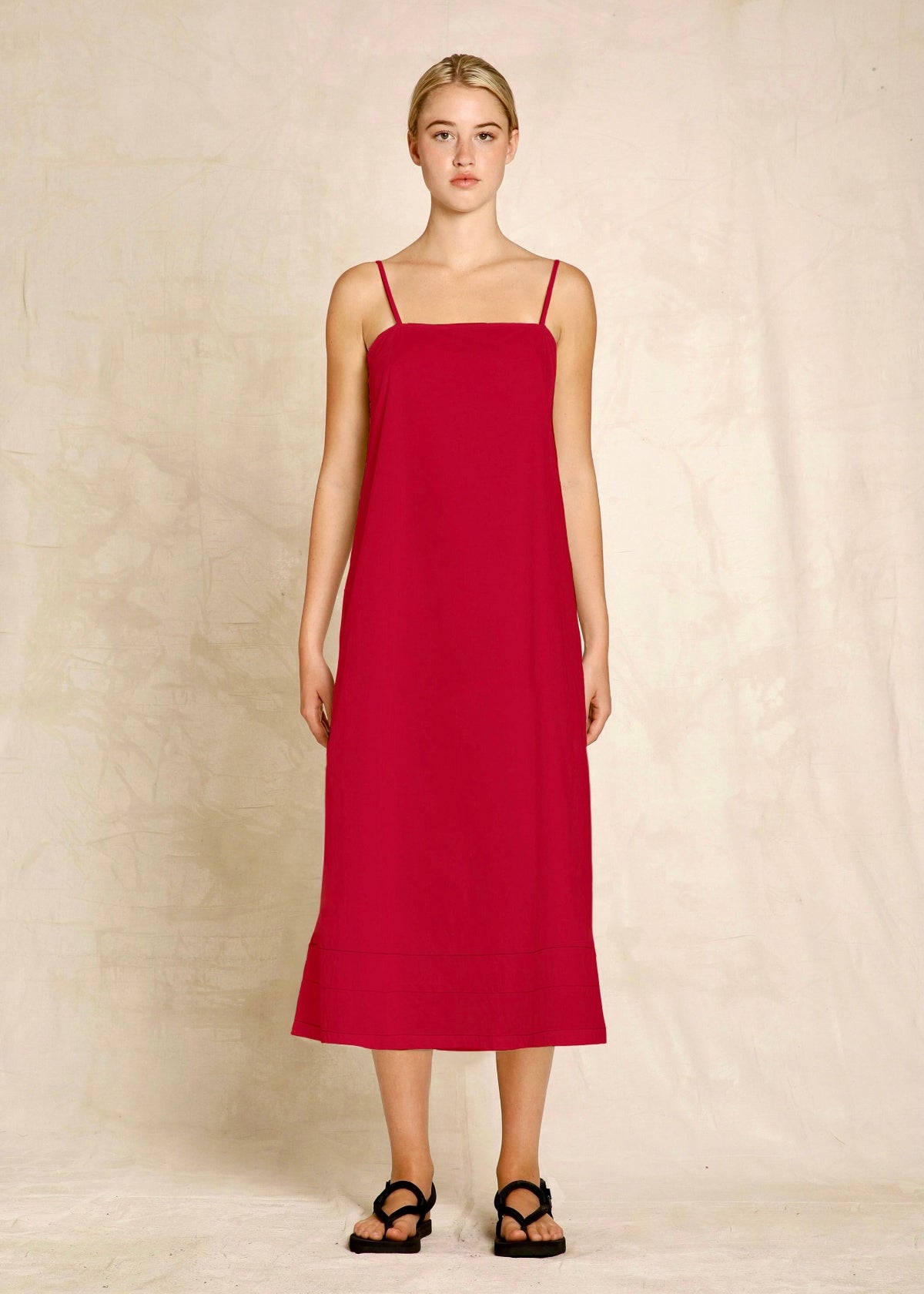 Woman wearing a red slip dress against a beige background