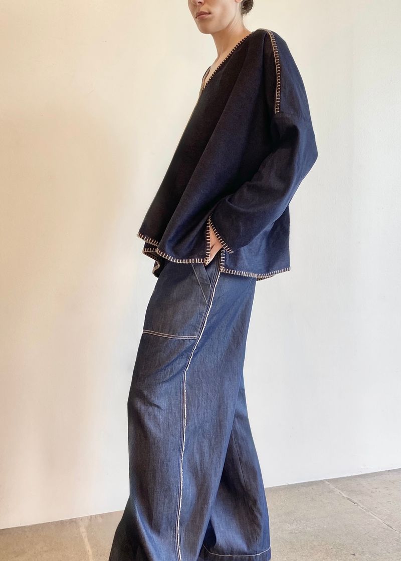 Navy blue denim Praia top with jeans on a hanger against a white background