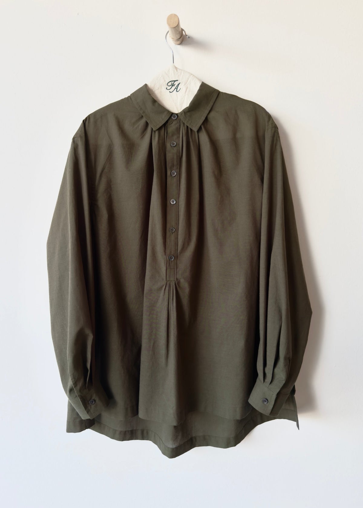 Green Agnes shirt on a hanger against a white background