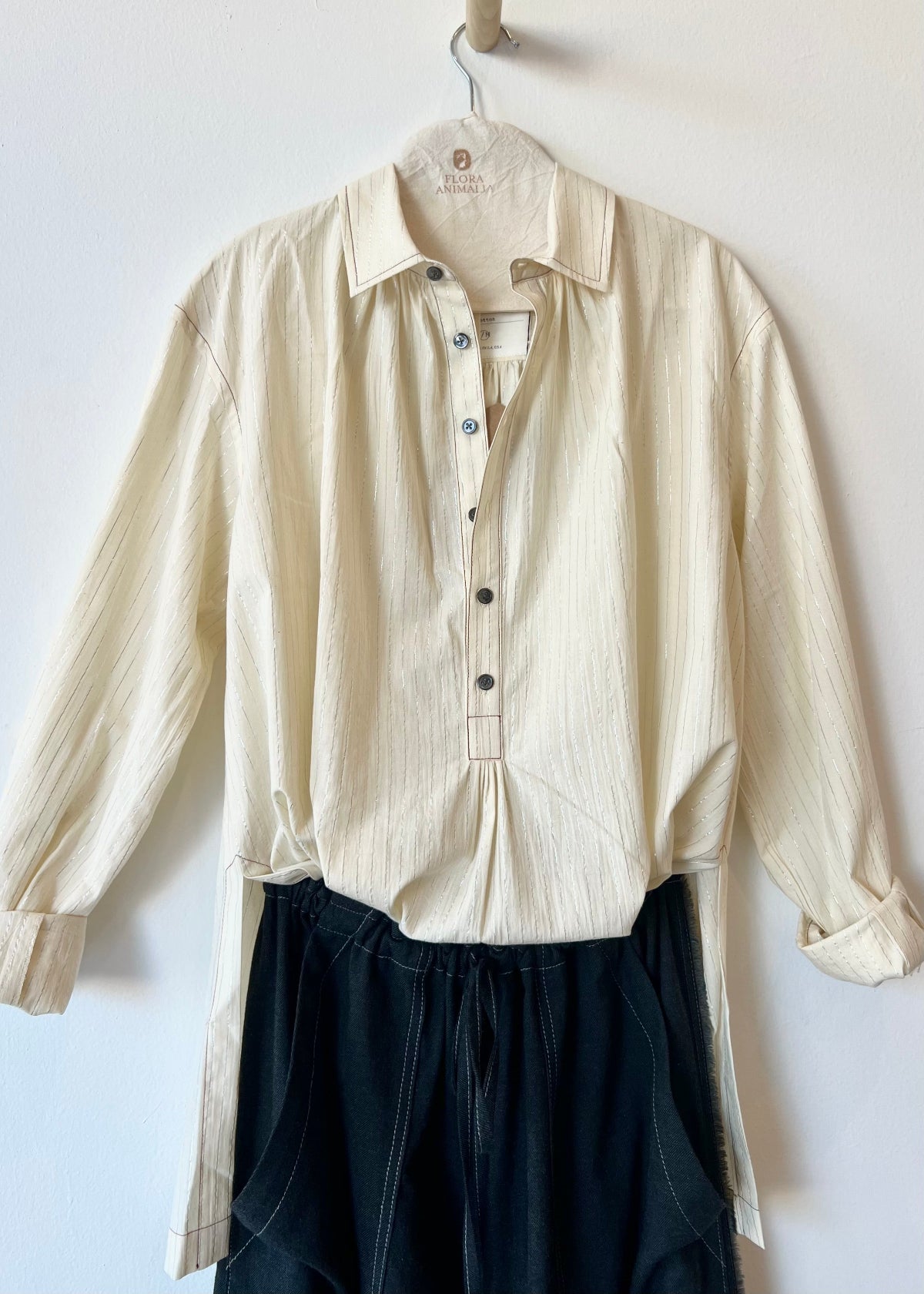 white shirt tucked in the front of black pants against a neutral wall