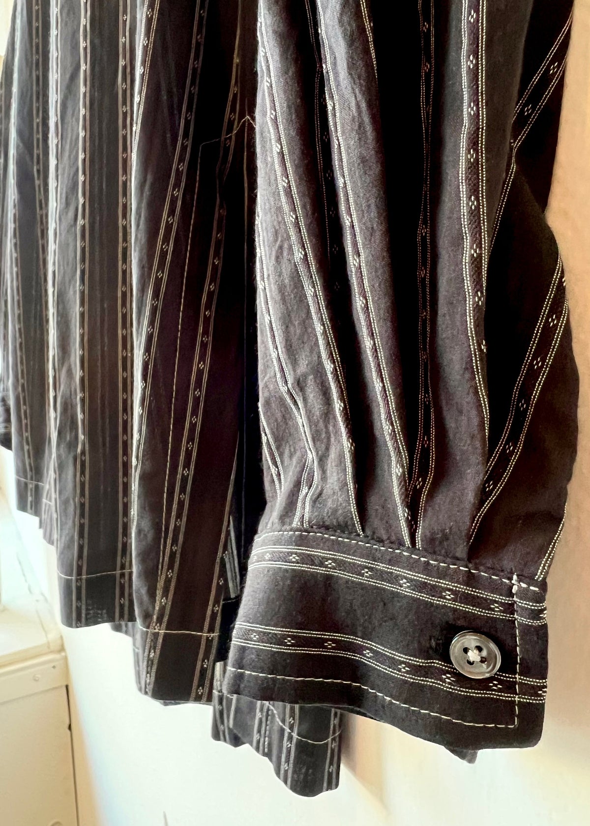 closeup of black shirt with white stripes sleeve cuff and hem