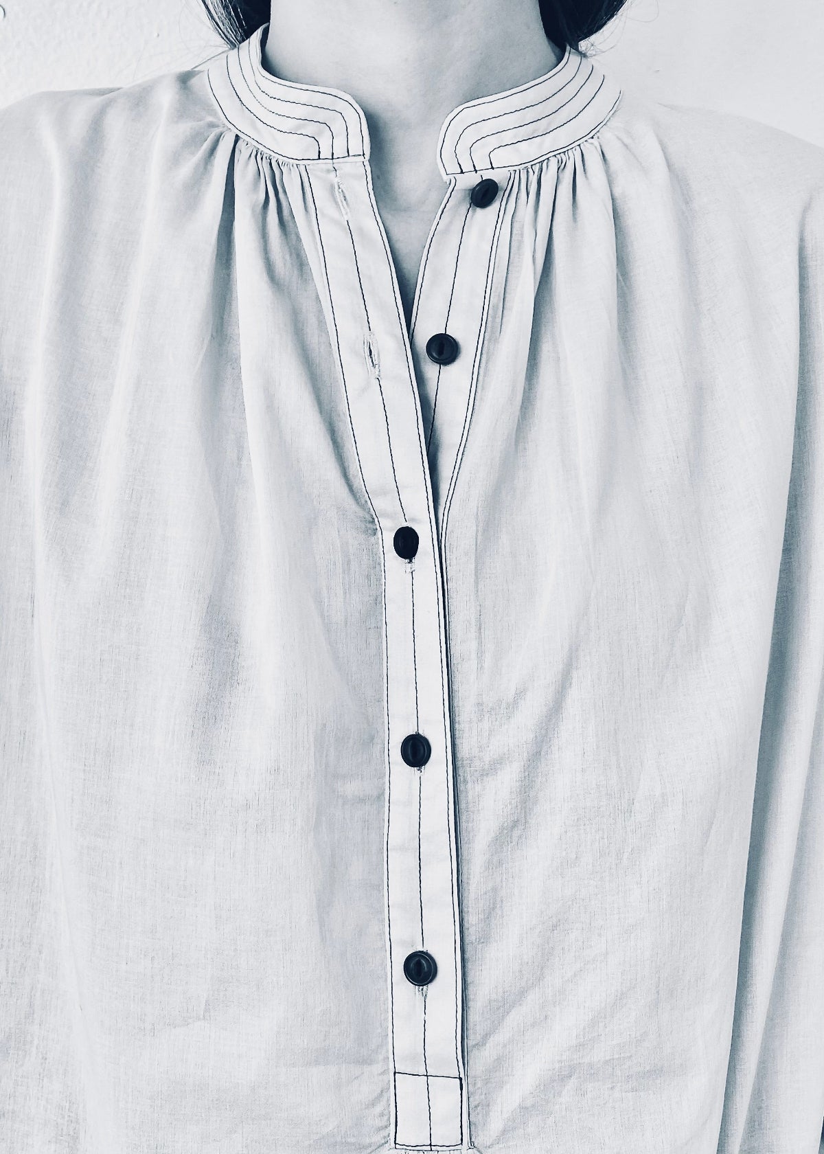Close-up of a white shirt with black buttons on a person