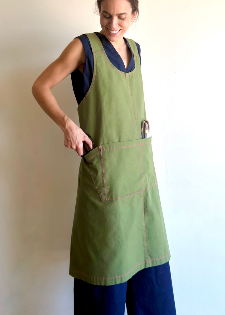 Model wearing Flora Animalia organic canvas harvest apron in purple grape, pocket and hardware detail, side view.
