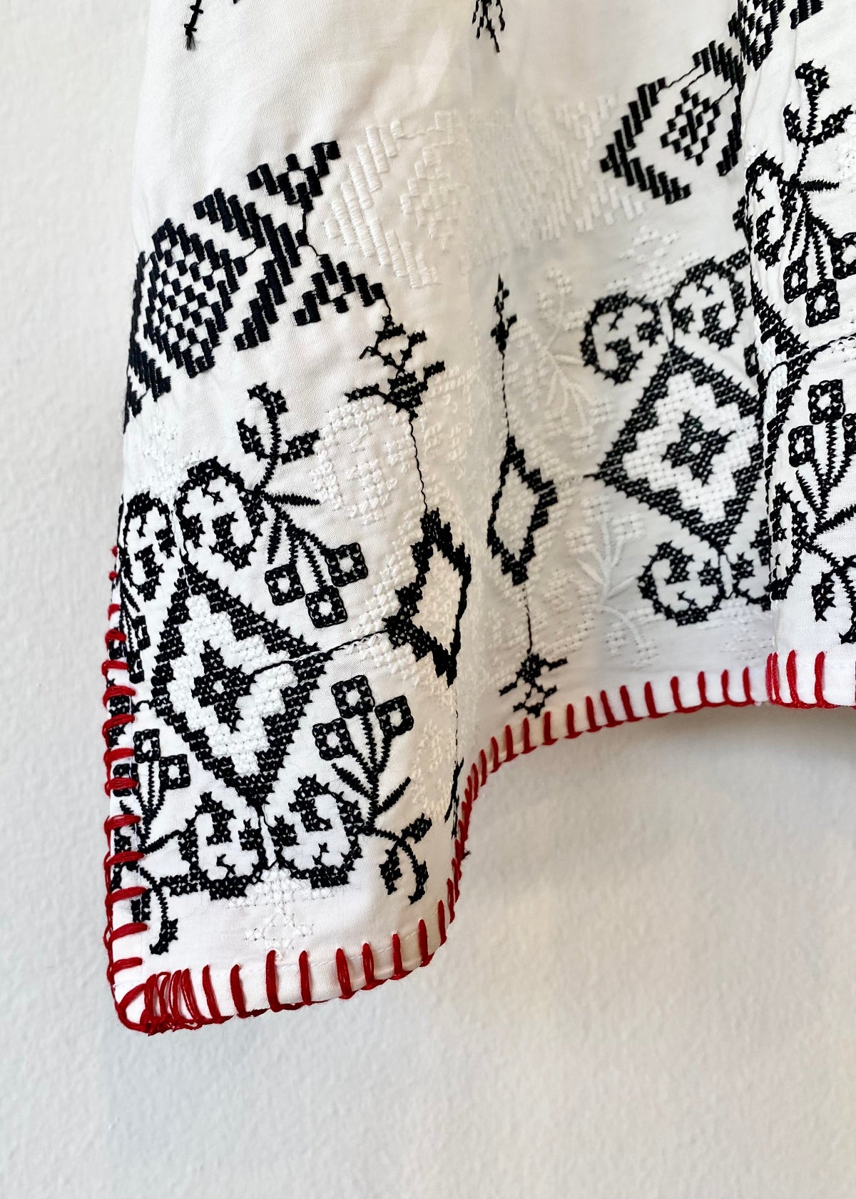 white embroidered tunic with red blanket stitching hem detail