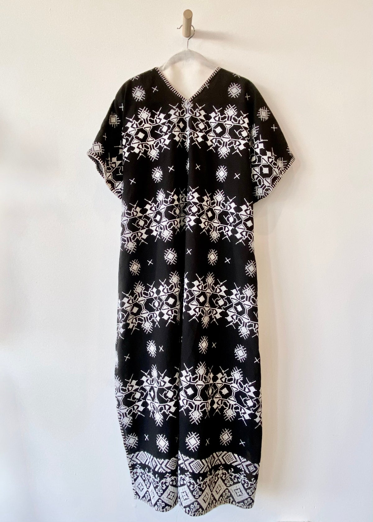 v-neck black caftan with white embroidery and blanket stitch edge front view