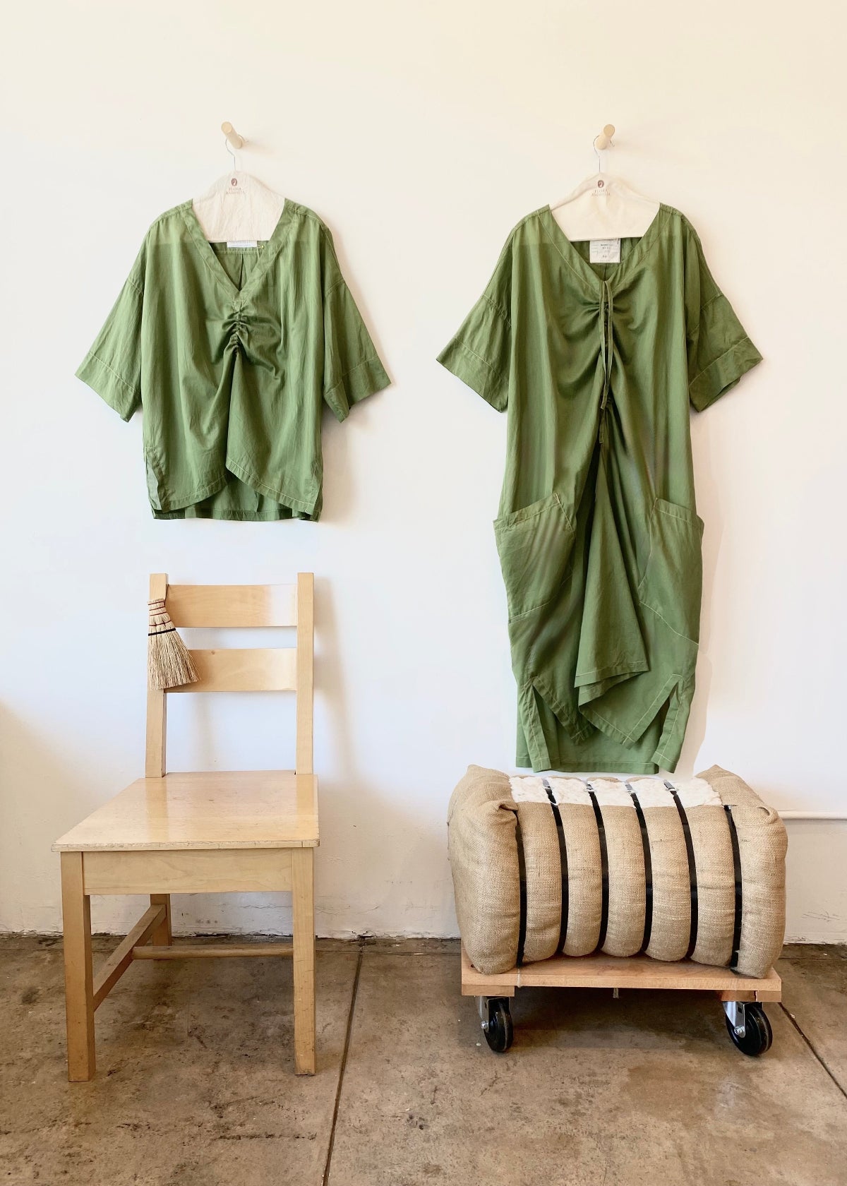 a green dress and green top hanging on a white wall