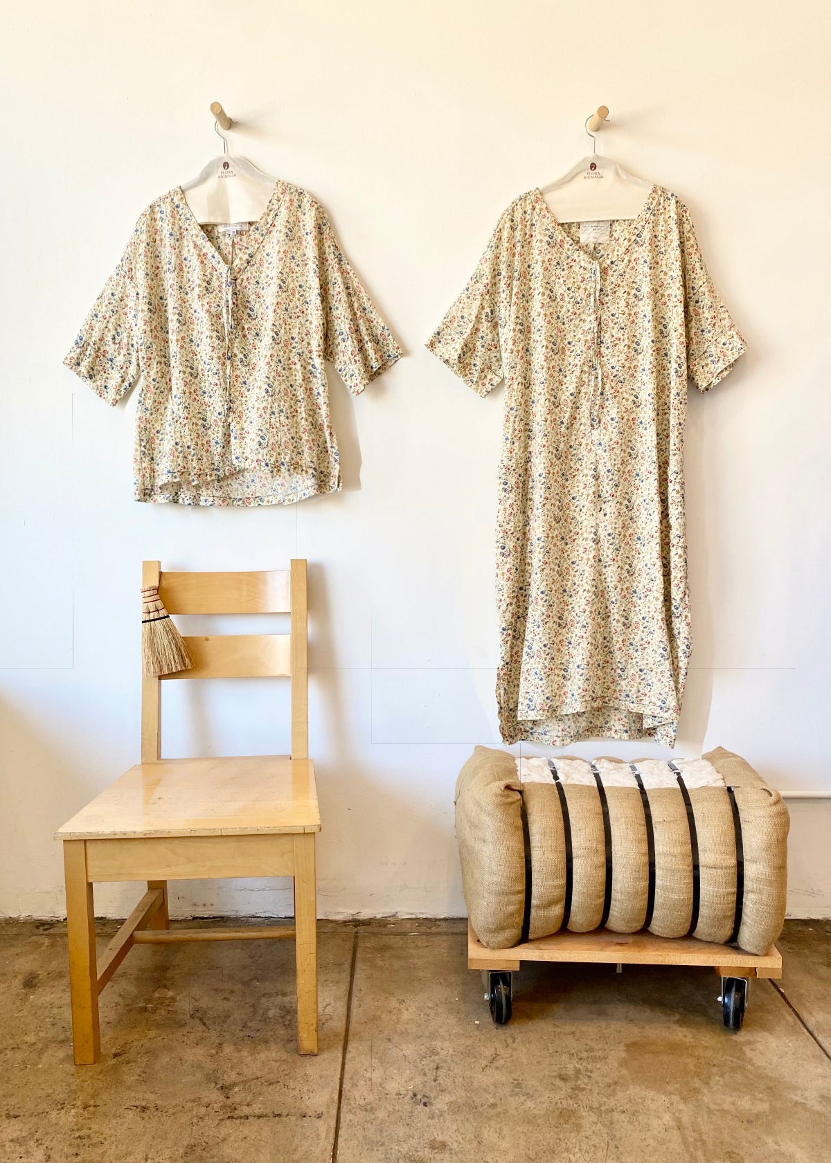 Two patterned shirts on hangers, against a white wall.
