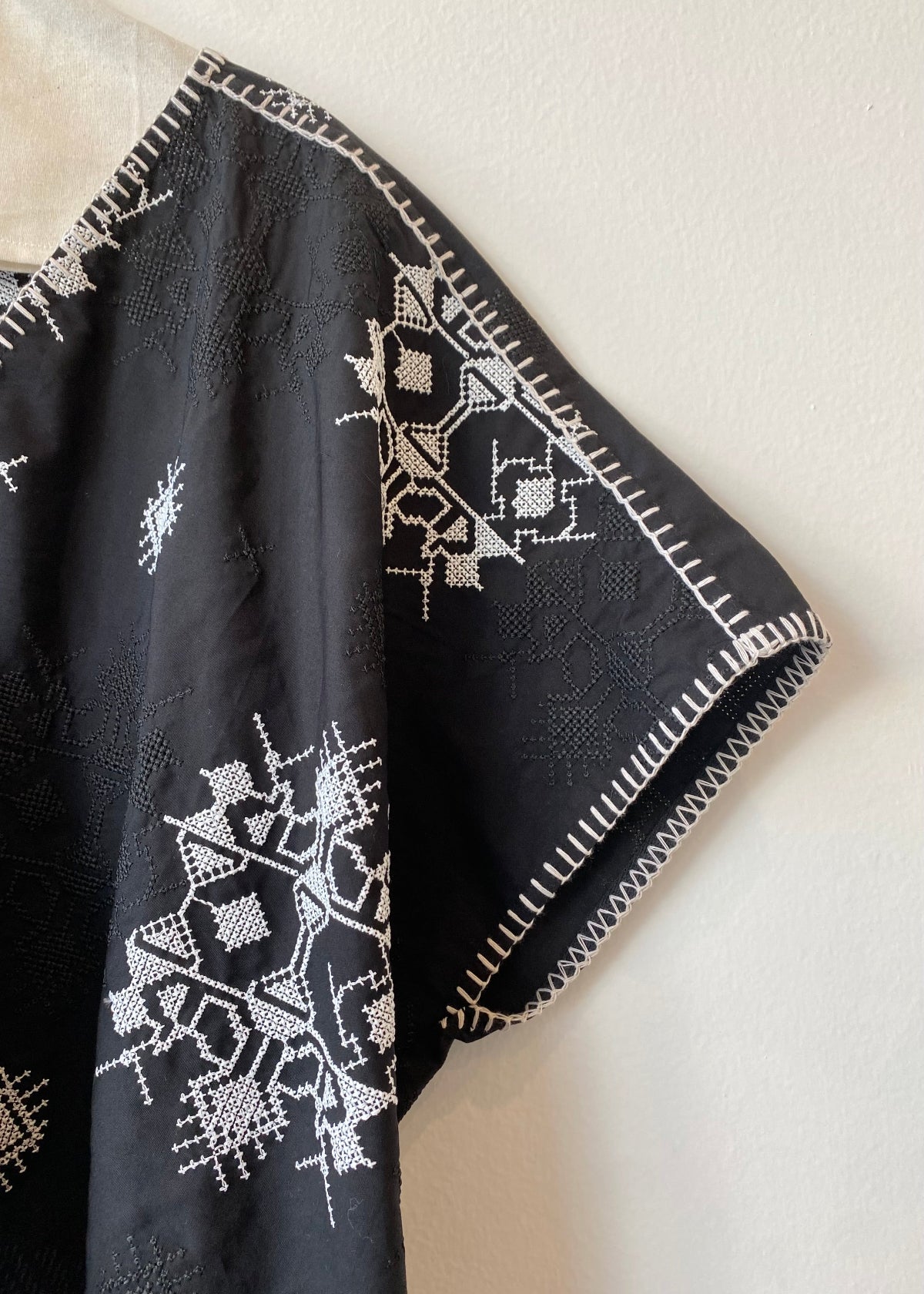 Black fabric with white embroidered patterns on a beige background