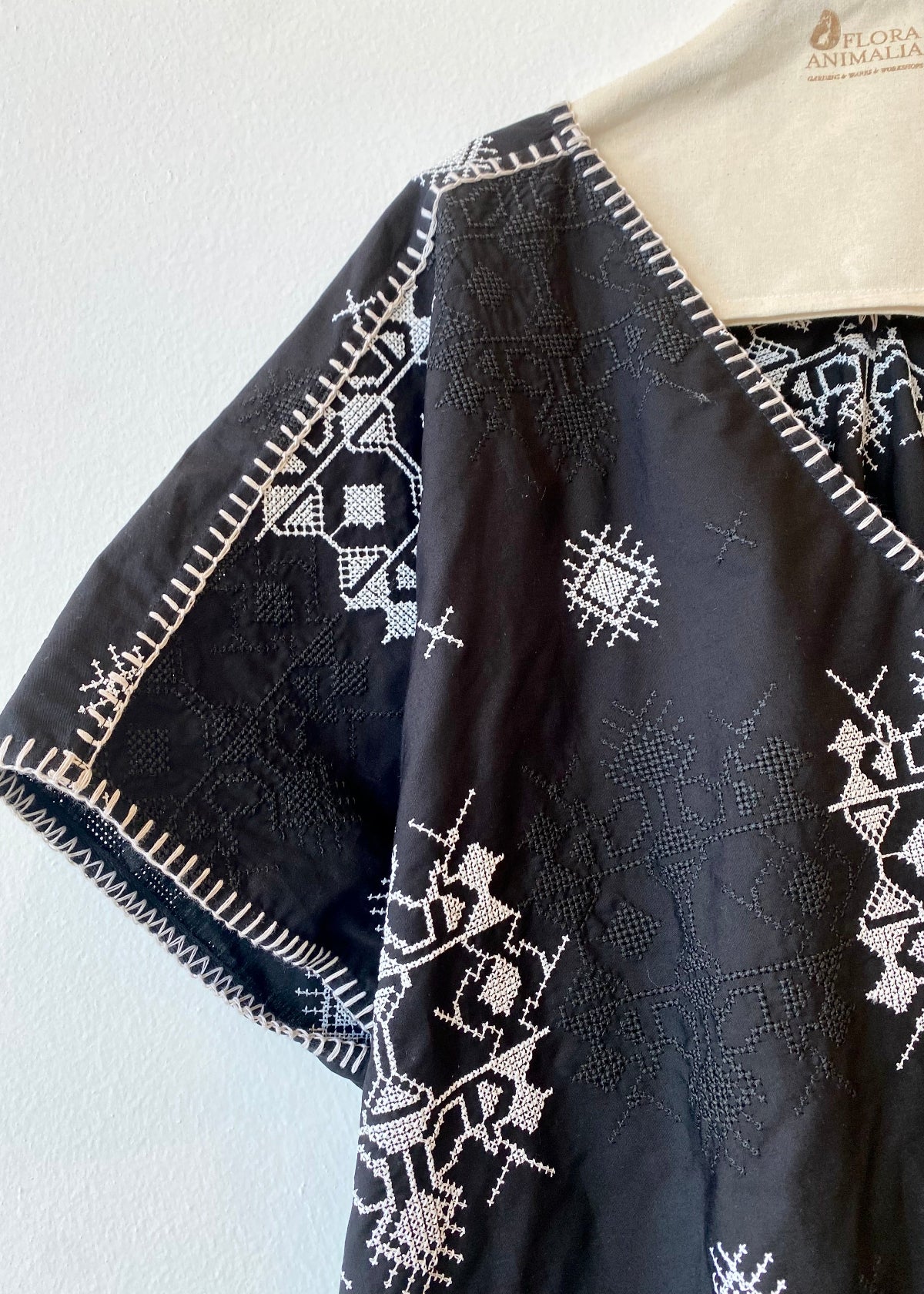 Black embroidered garment on a hanger against a white background