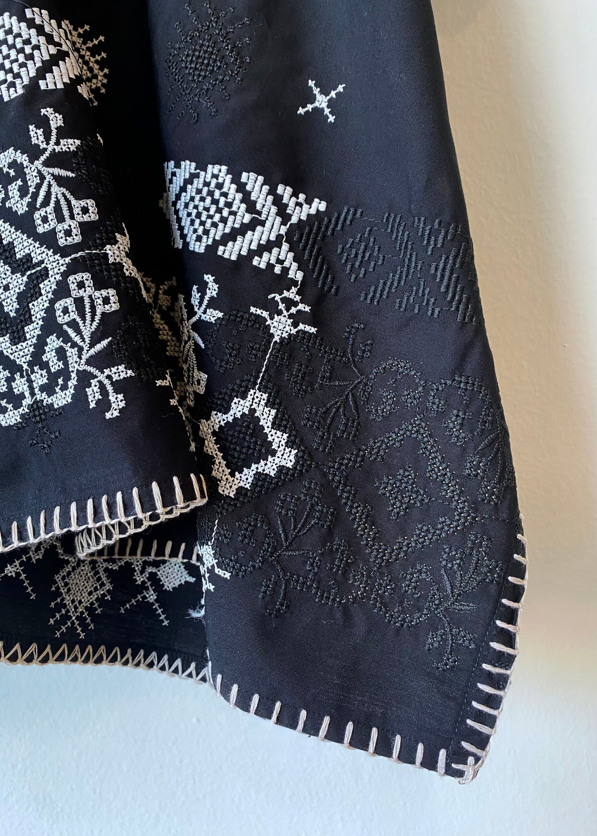 Black fabric with white and black embroidery patterns on a light background