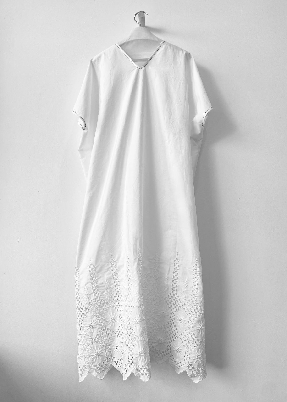 back of White dress with embroidery details on a hanger against a white background