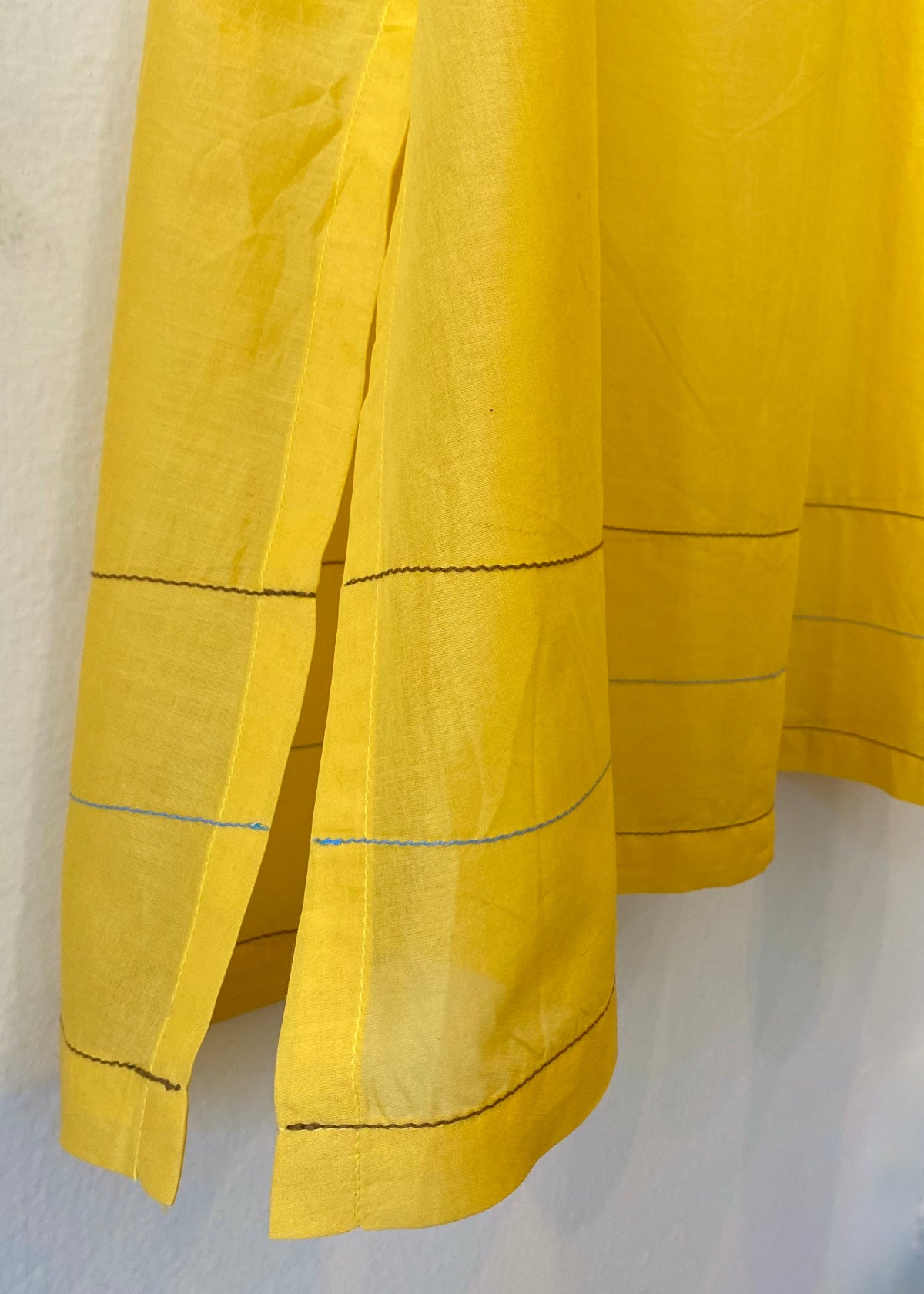 Yellow fabric with blue and brown stitching on a white background