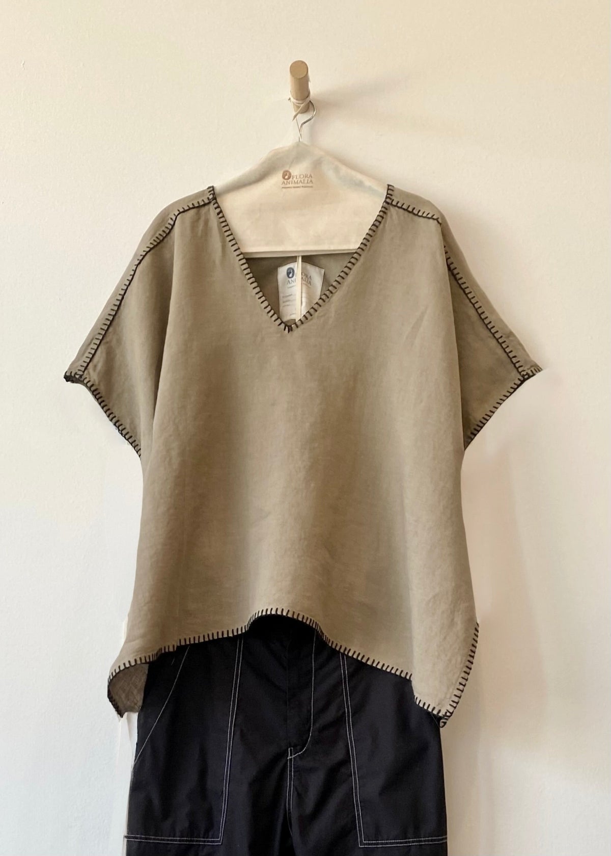 khaki top with black pants on a hanger against a white background