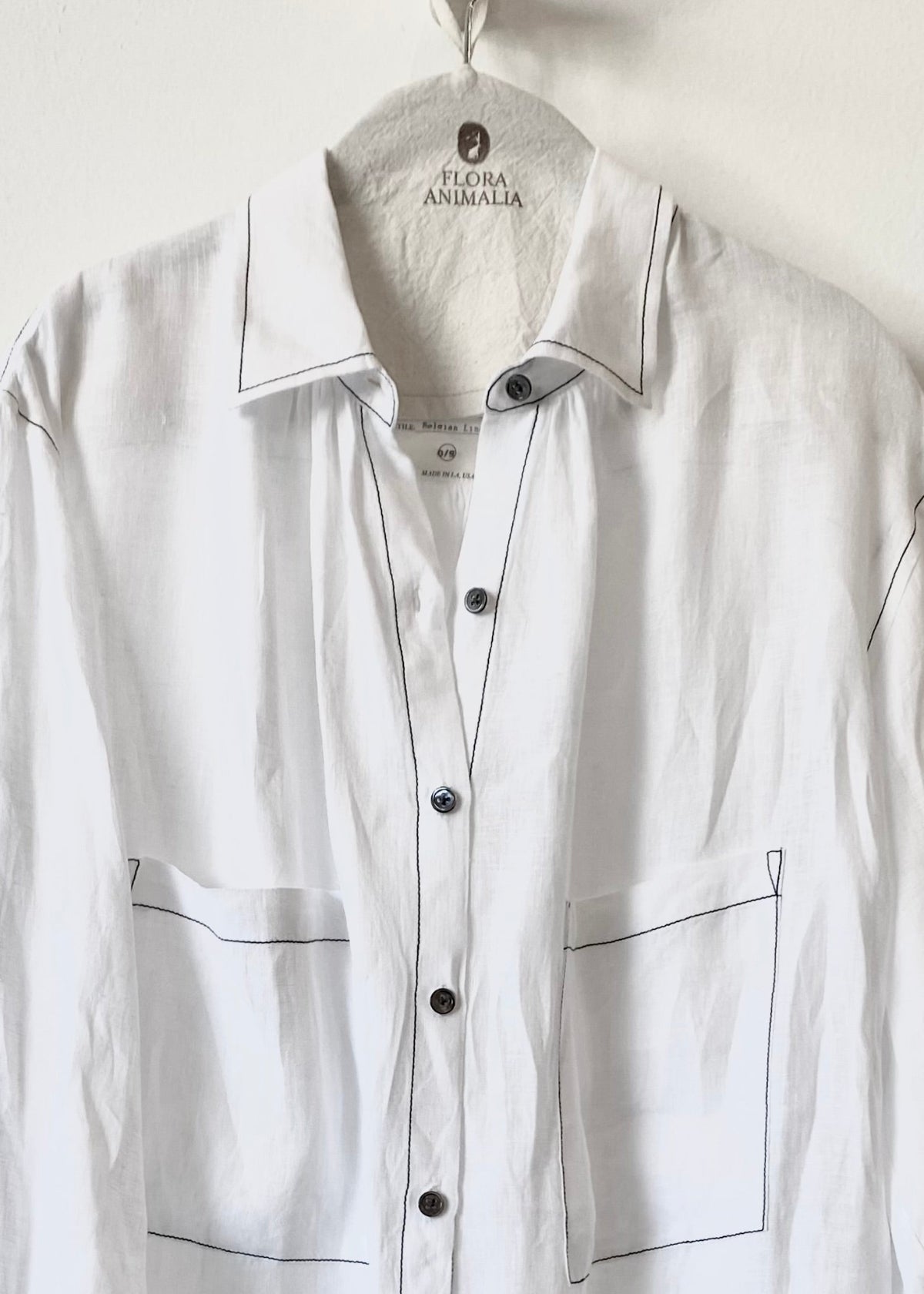 2 pocket White button shirt with black accents on a hanger with 'Flora Animalia' label.