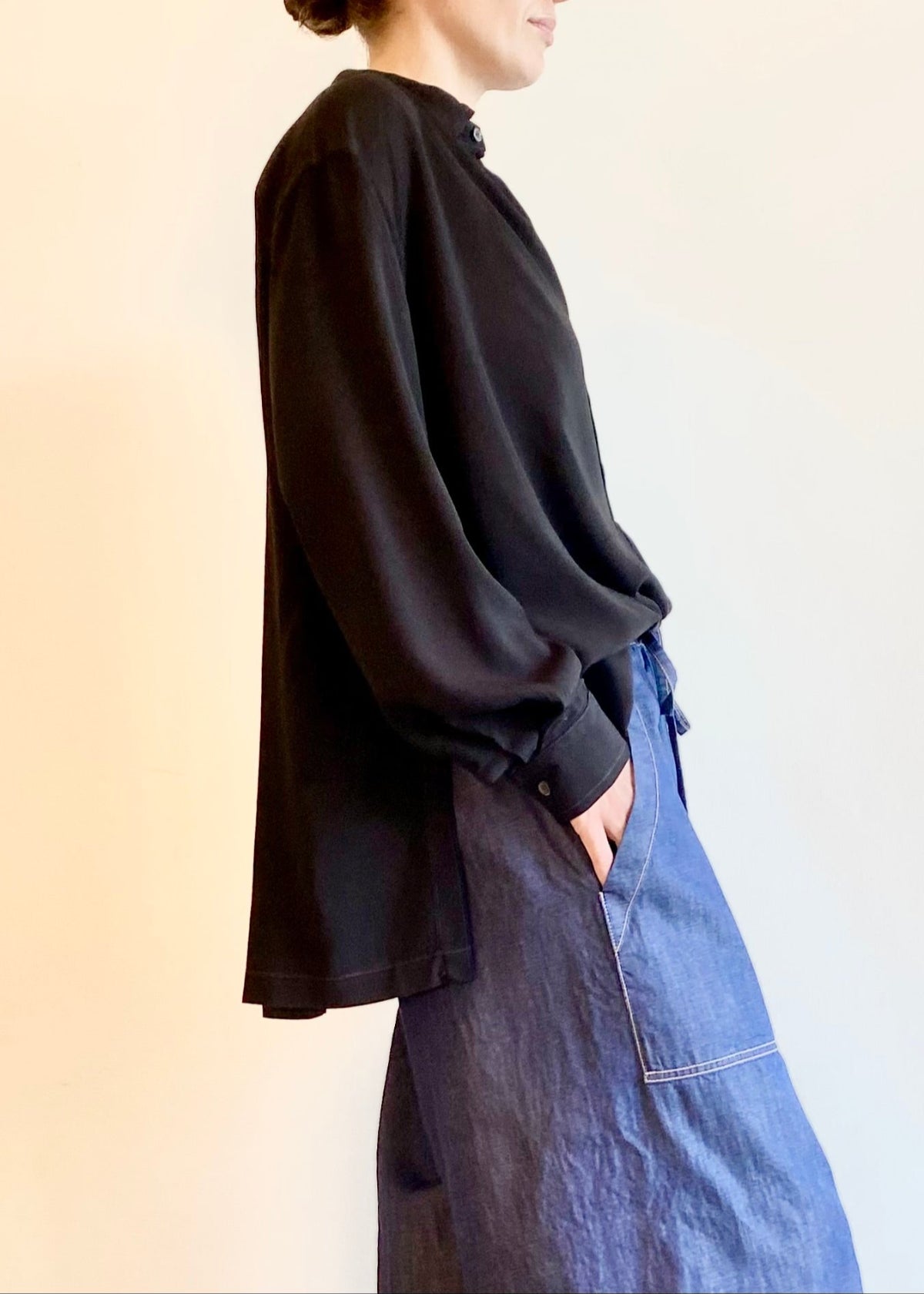 Person wearing a black button Agnes shirt and drawstring blue jeans against a plain background