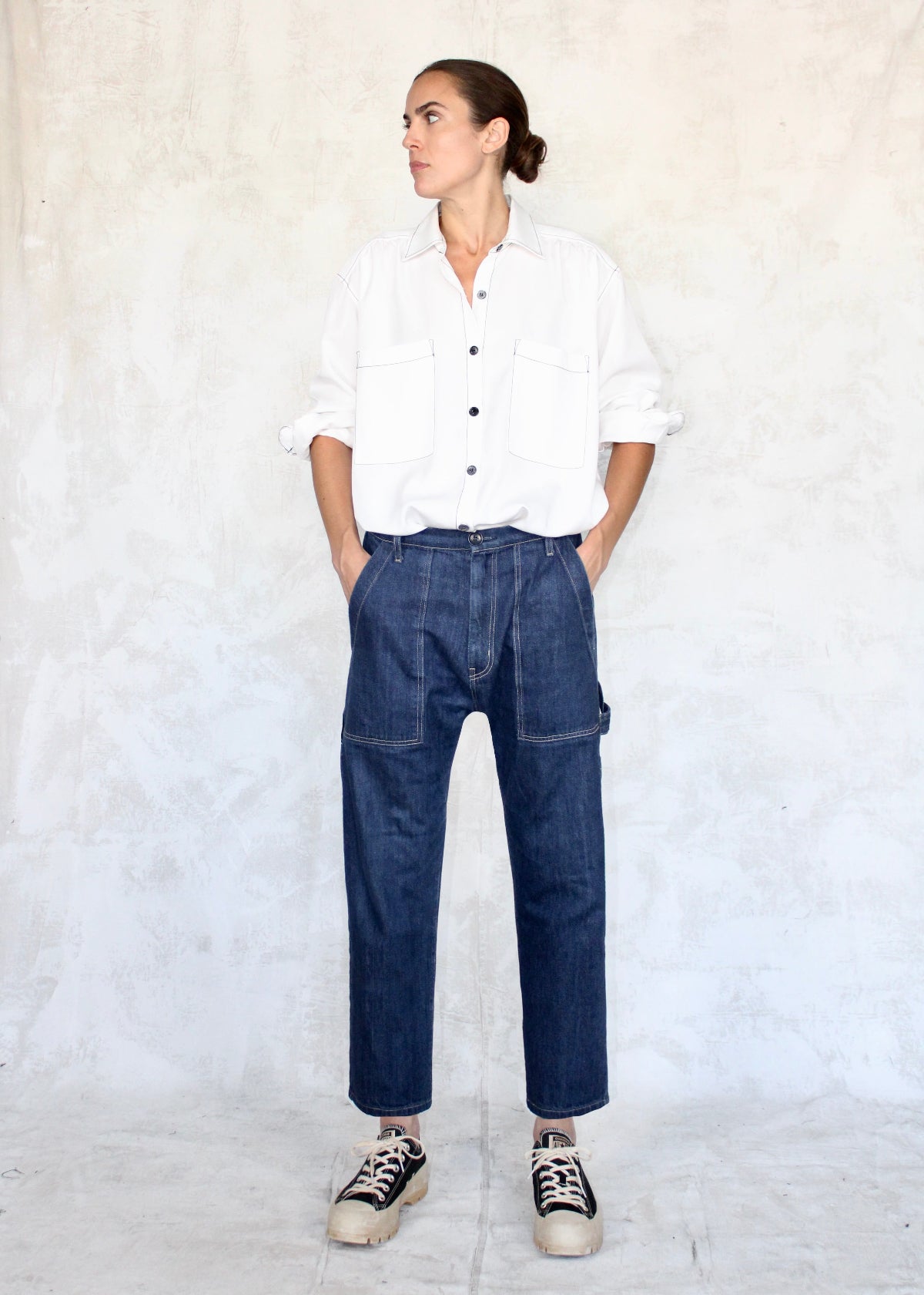 Model wearing white button down shirt and cropped indigo denim Maker's pant