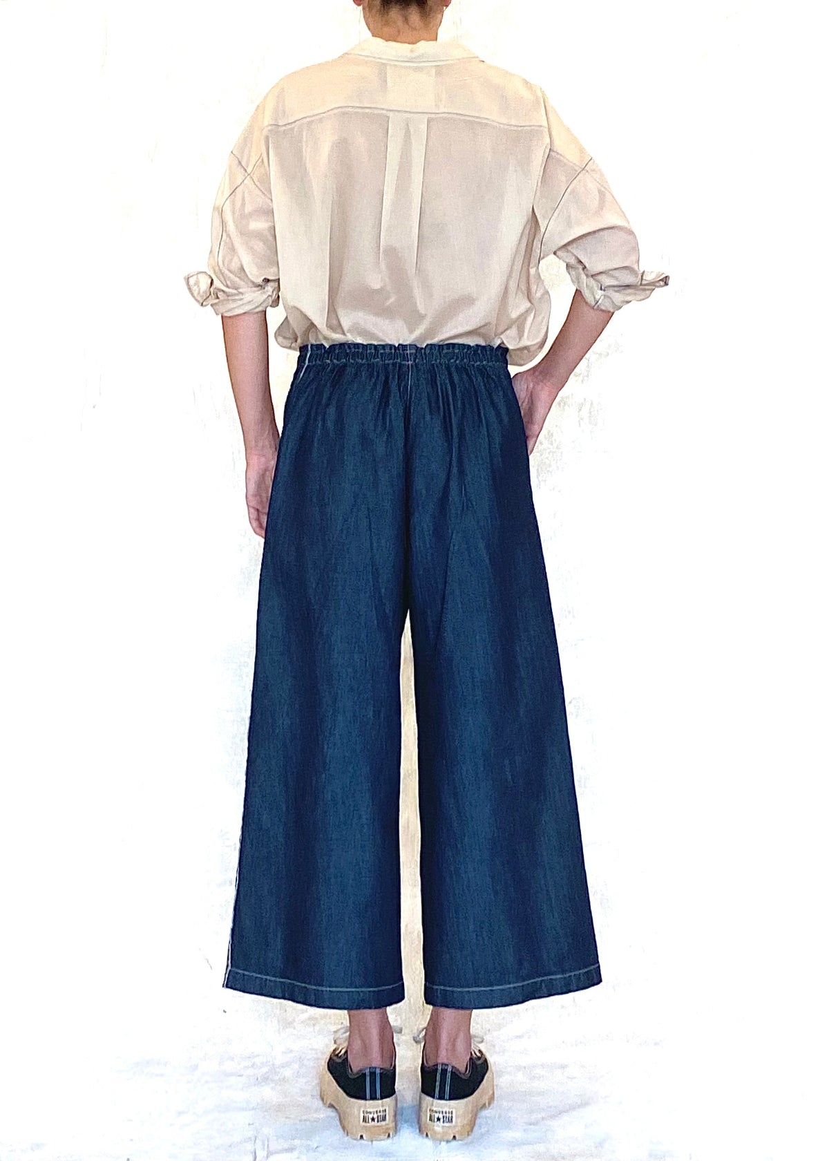 denim drawstring jeans with beige top pushed up sleeves rear view