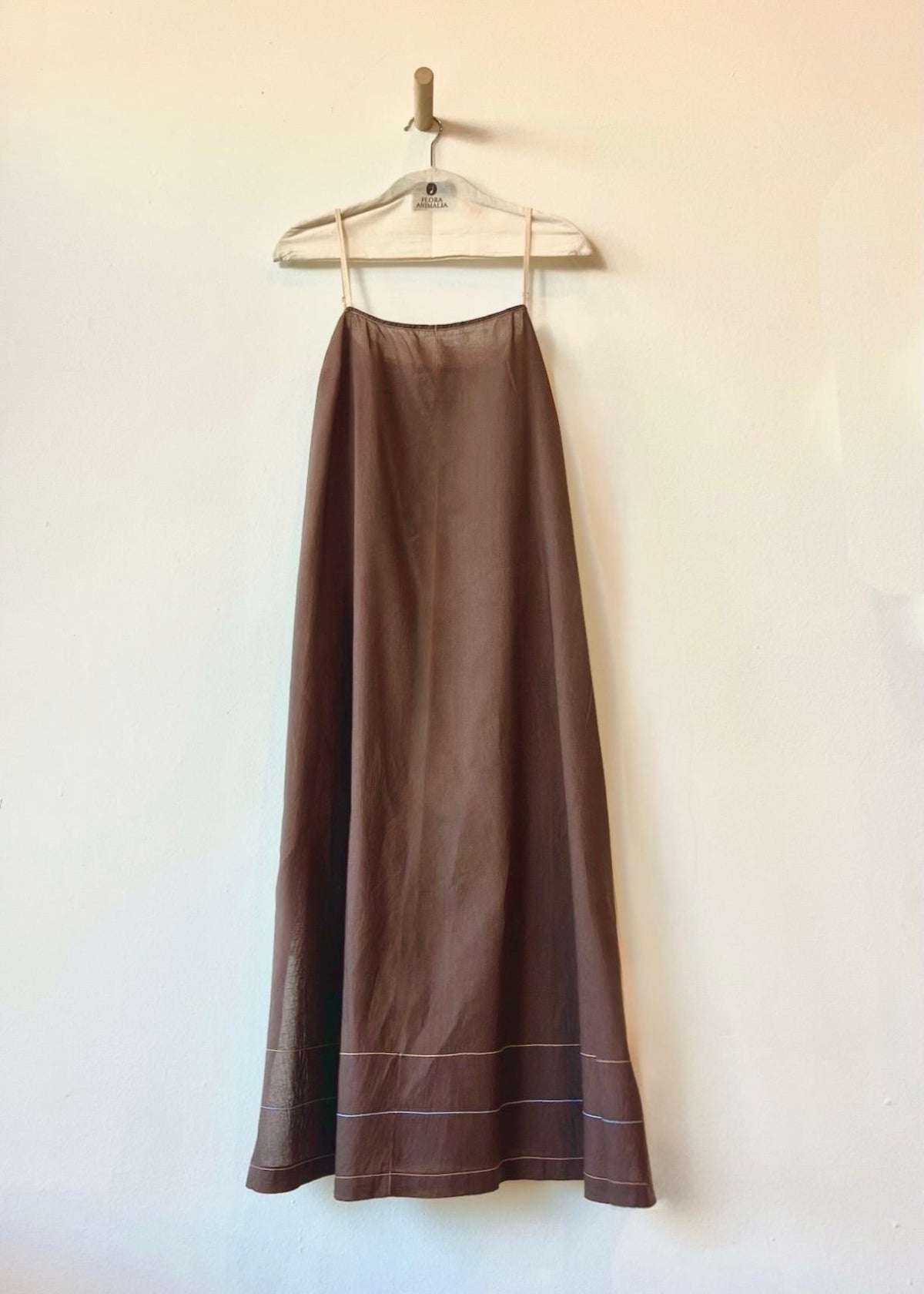 Brown dress hanging on a hanger against a white wall