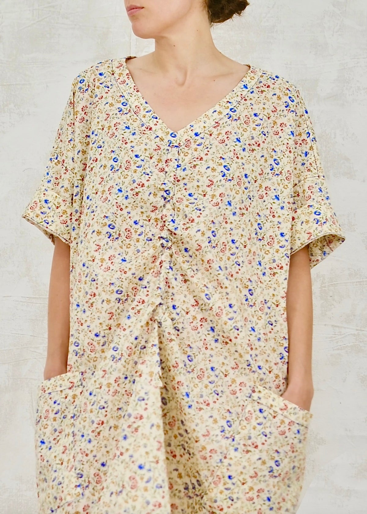 Person wearing a floral dress against a plain background