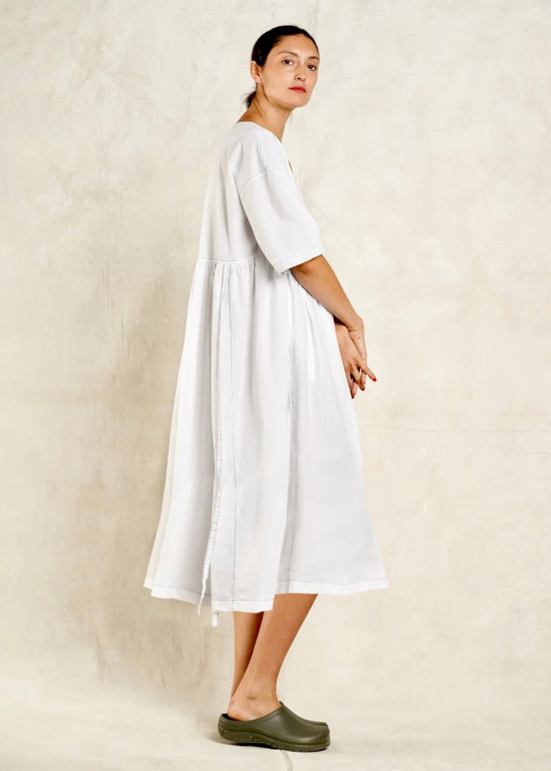 Woman wearing a white dress standing against a plain background