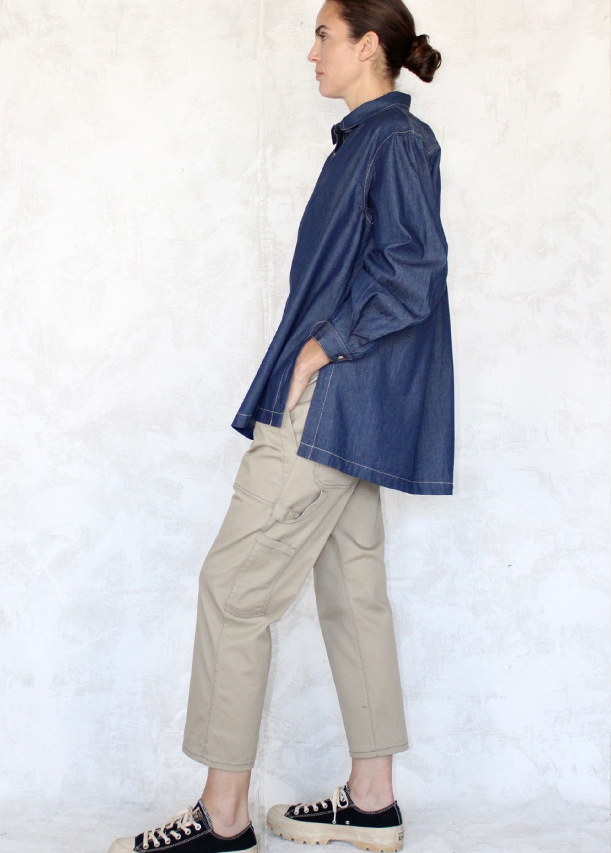 side view denim loose top with beige pants agains neutral color background