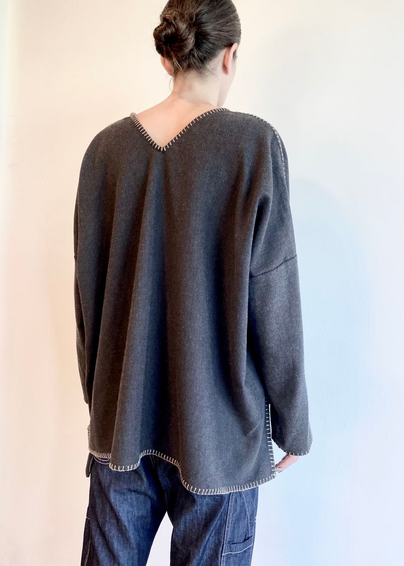 rear view of Person wearing a dark gray sweater with a v neck in back