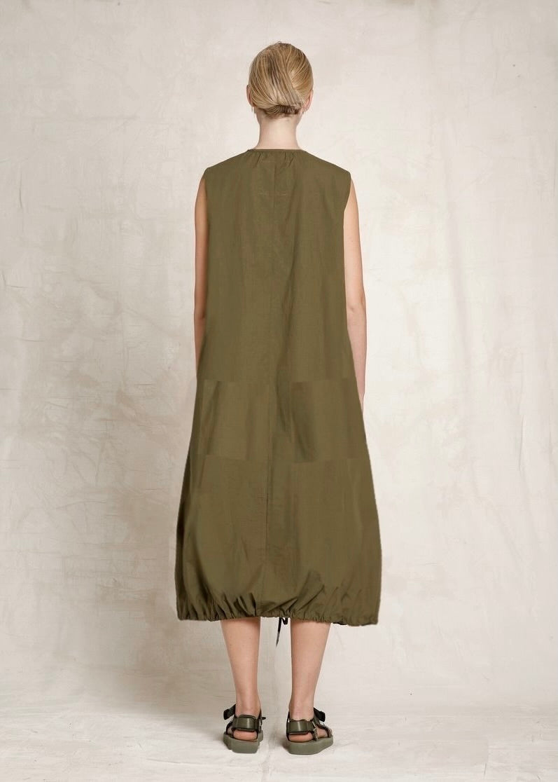 Person wearing a green sleeveless dress against a plain background