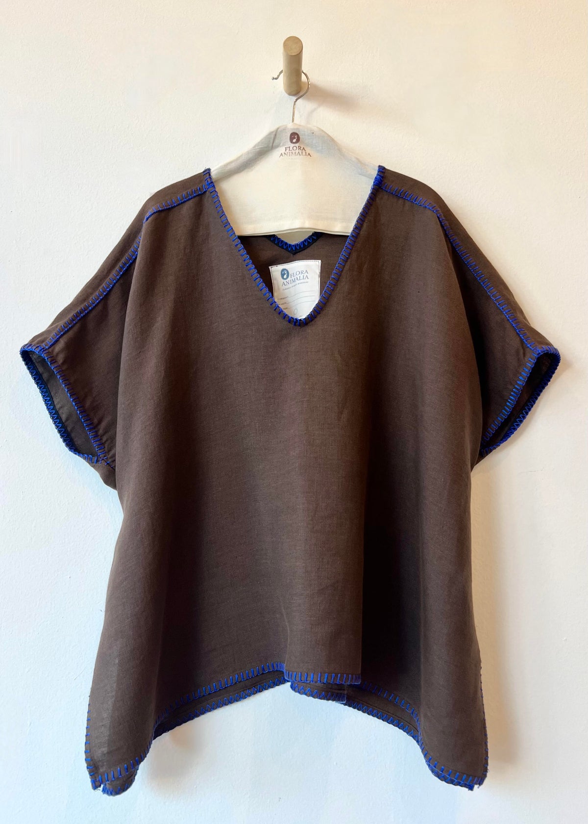 Brown poncho with blue trim on a hanger against a white background