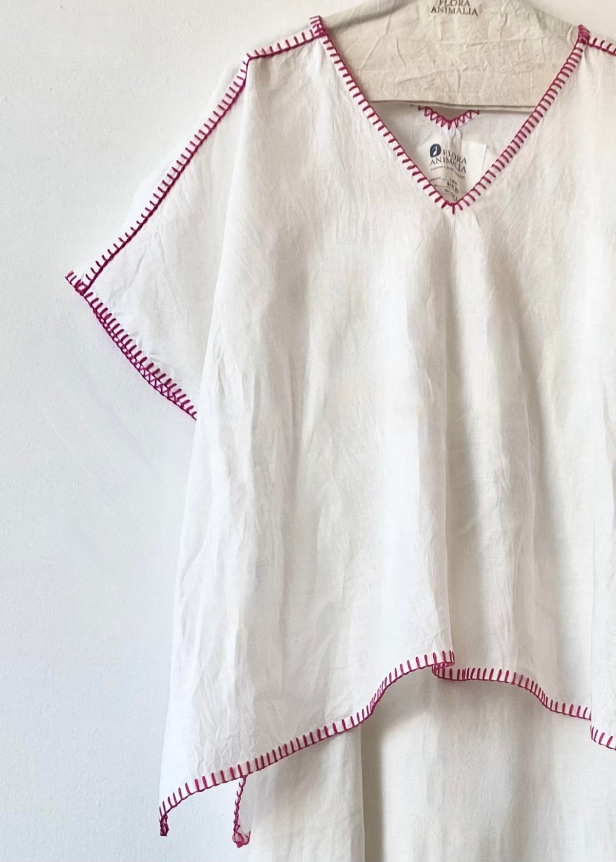 White blouse with red trim on a hanger against a white background