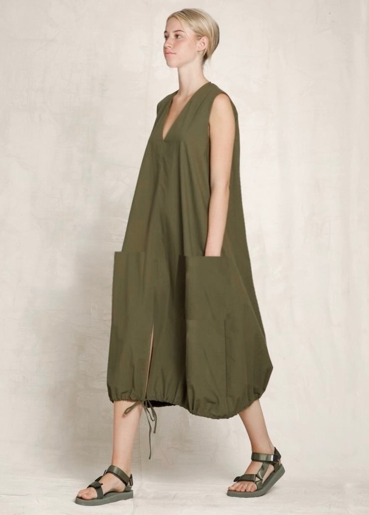 Woman wearing a green sleeveless dress with a plain background