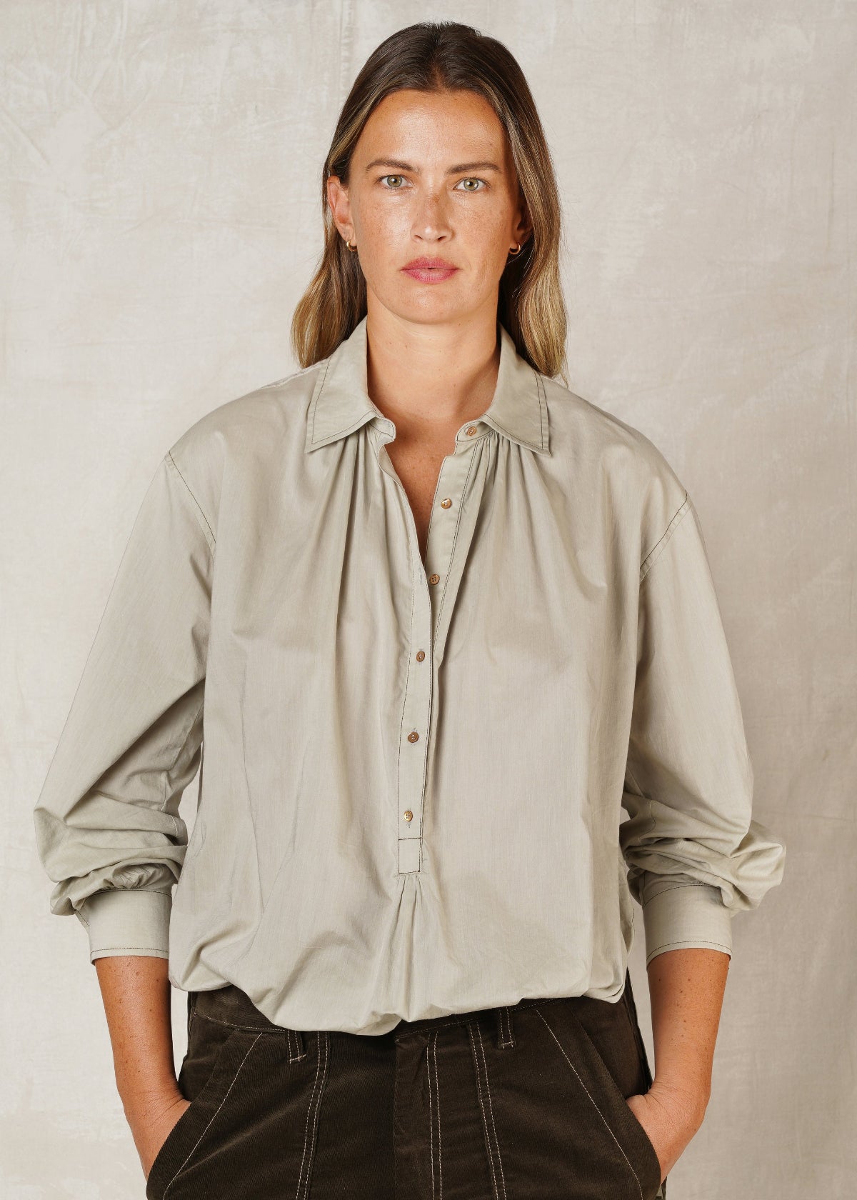 model in sea foam green button collar top with sleeves pushed up