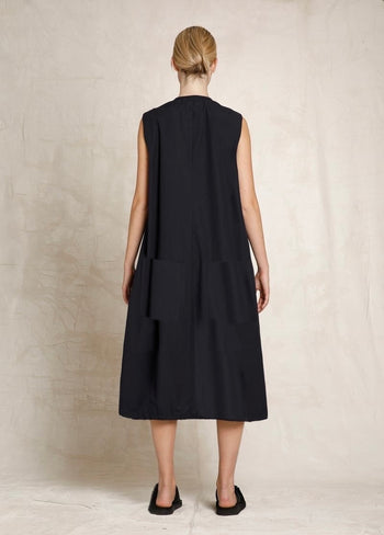 Woman wearing a black sleeveless dress against a neutral background