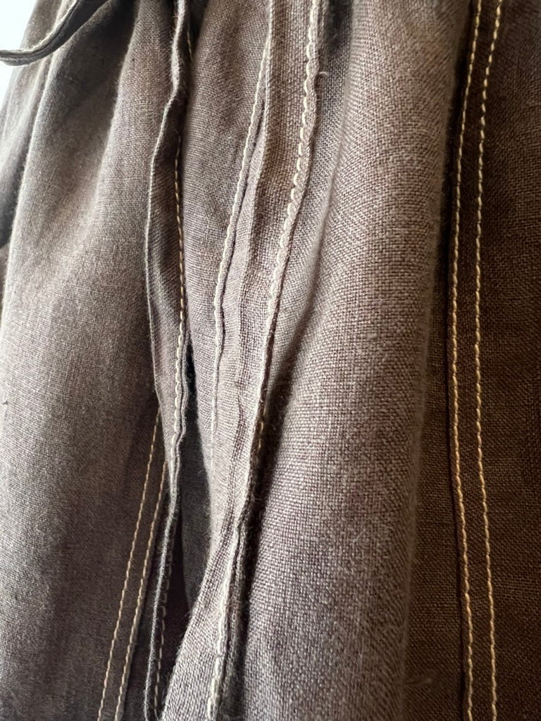 close up of brown linen with tan stitching on seams and waist ties